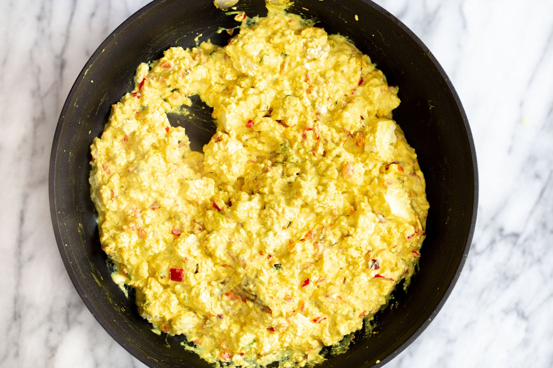 tofu scramble seasoning vegan tofu scramble being prepared in a black skillet