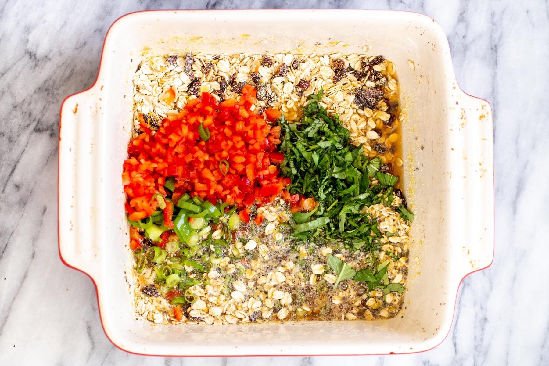 savory oatmeal bake bell peppers and spring onions being added to dry ingredients in a casserole dish