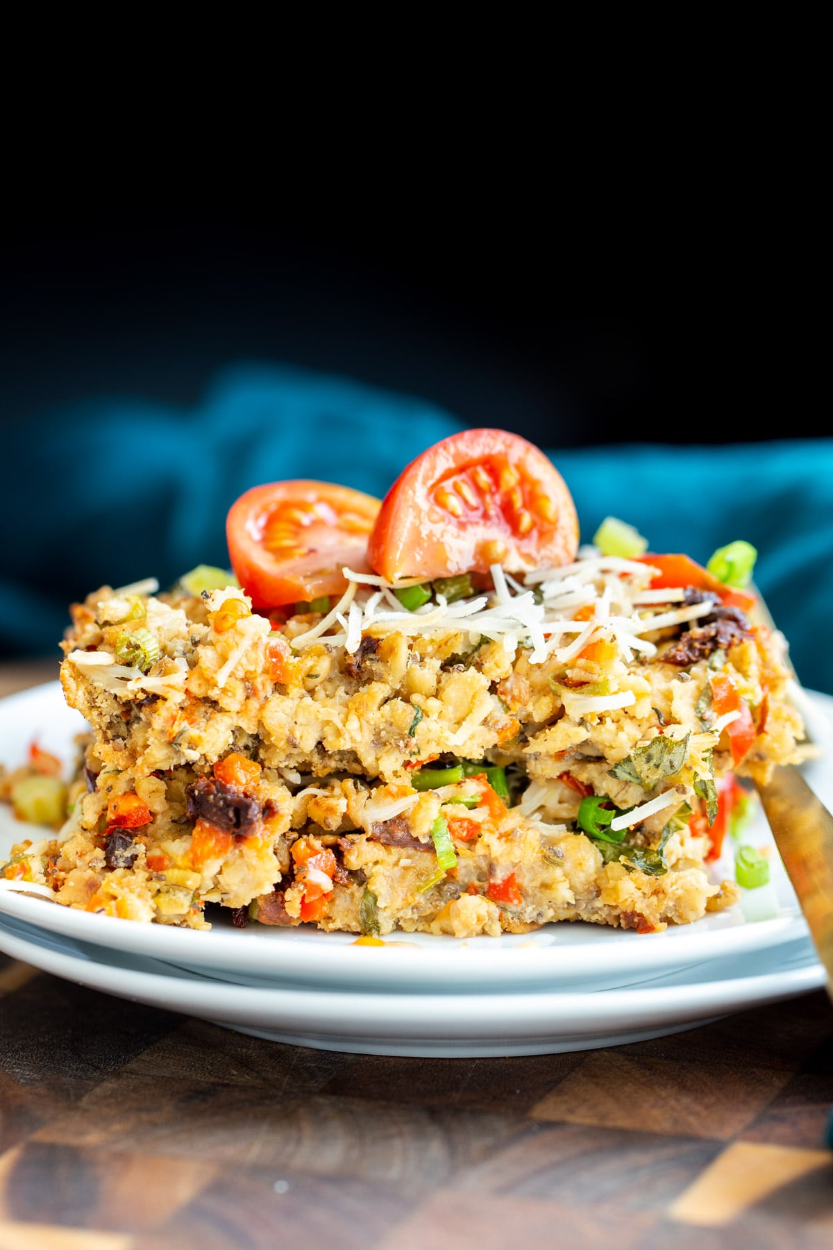 savory oatmeal bake a slice of savory oatmeal bake topped with parmesan cheese and tomatoes