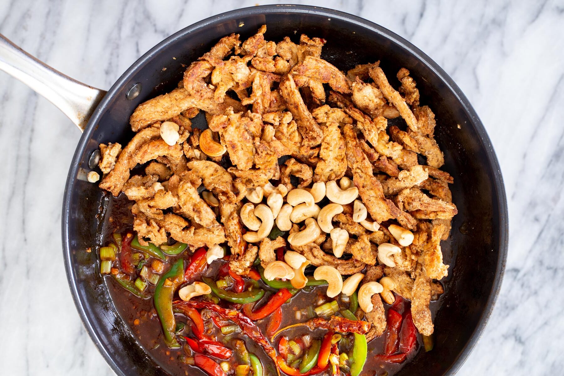 soycurls and cashew nuts being added to stir-fried veggies