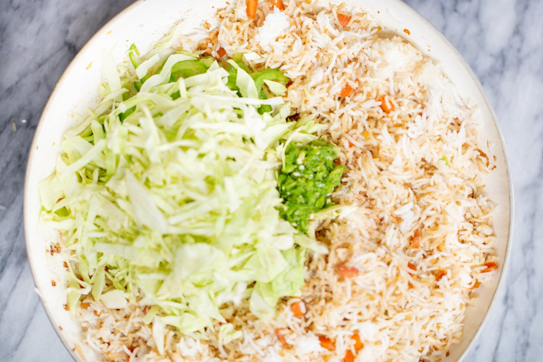 shredded cabbage being added to a pan with fried rice