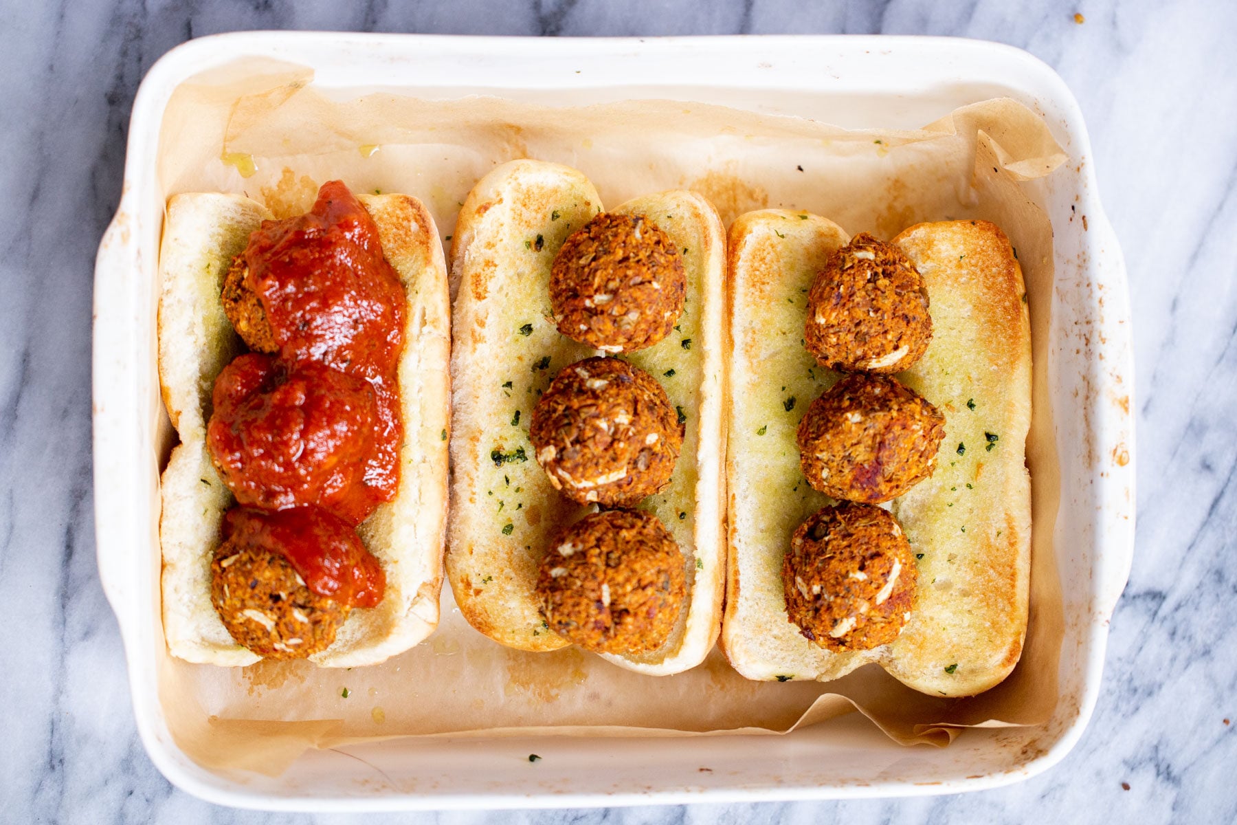 vegan meatball subs a casserole dish with vegan meatball subs topped with lentil meatballs and marinara sauce