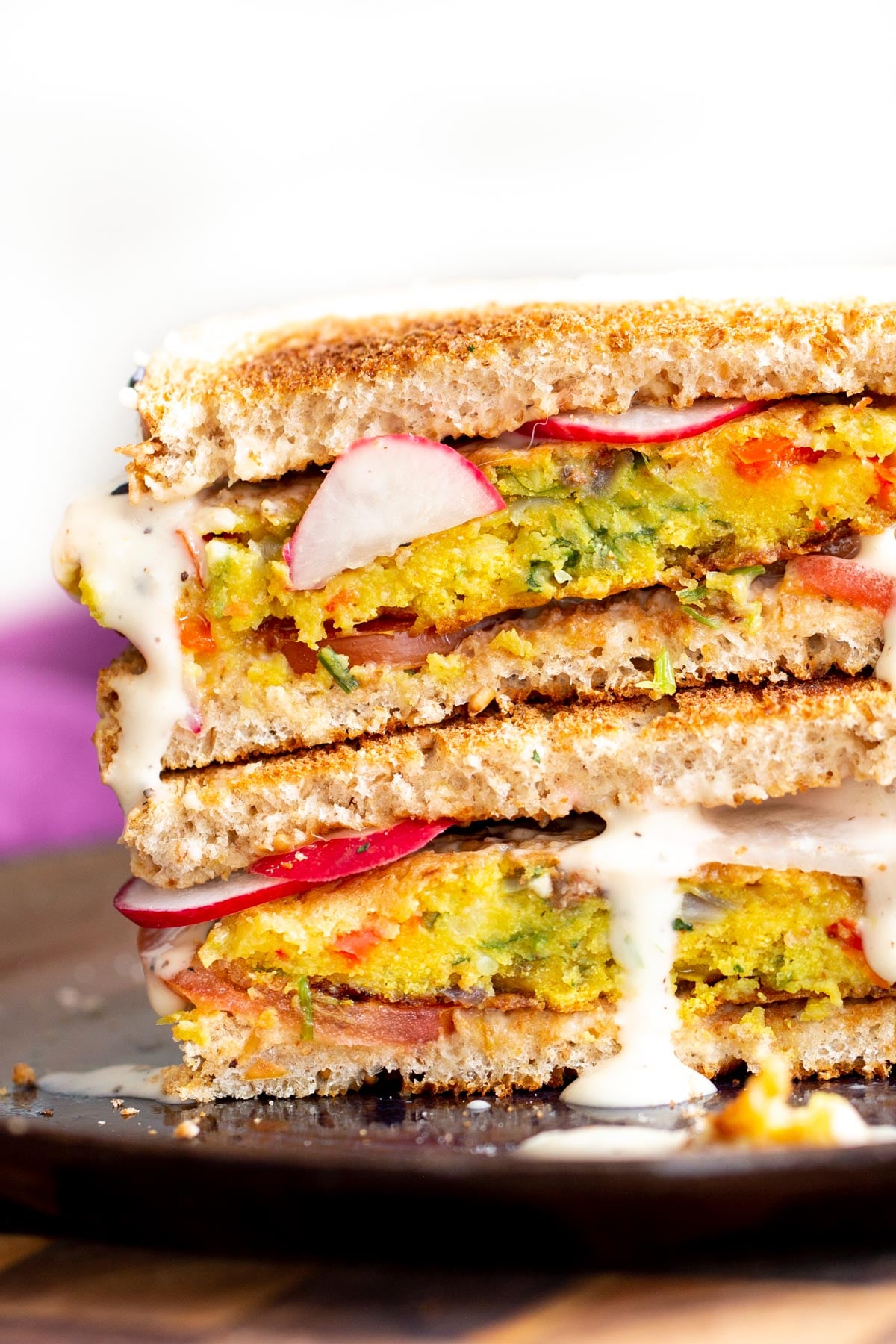stacked vegan breakfast sandwich filled with chickpea flour pancakes and vegetables