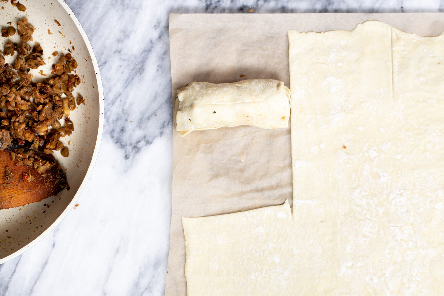 vegan sausage rolls thawed puff pastry being rolled out on a marble countertop