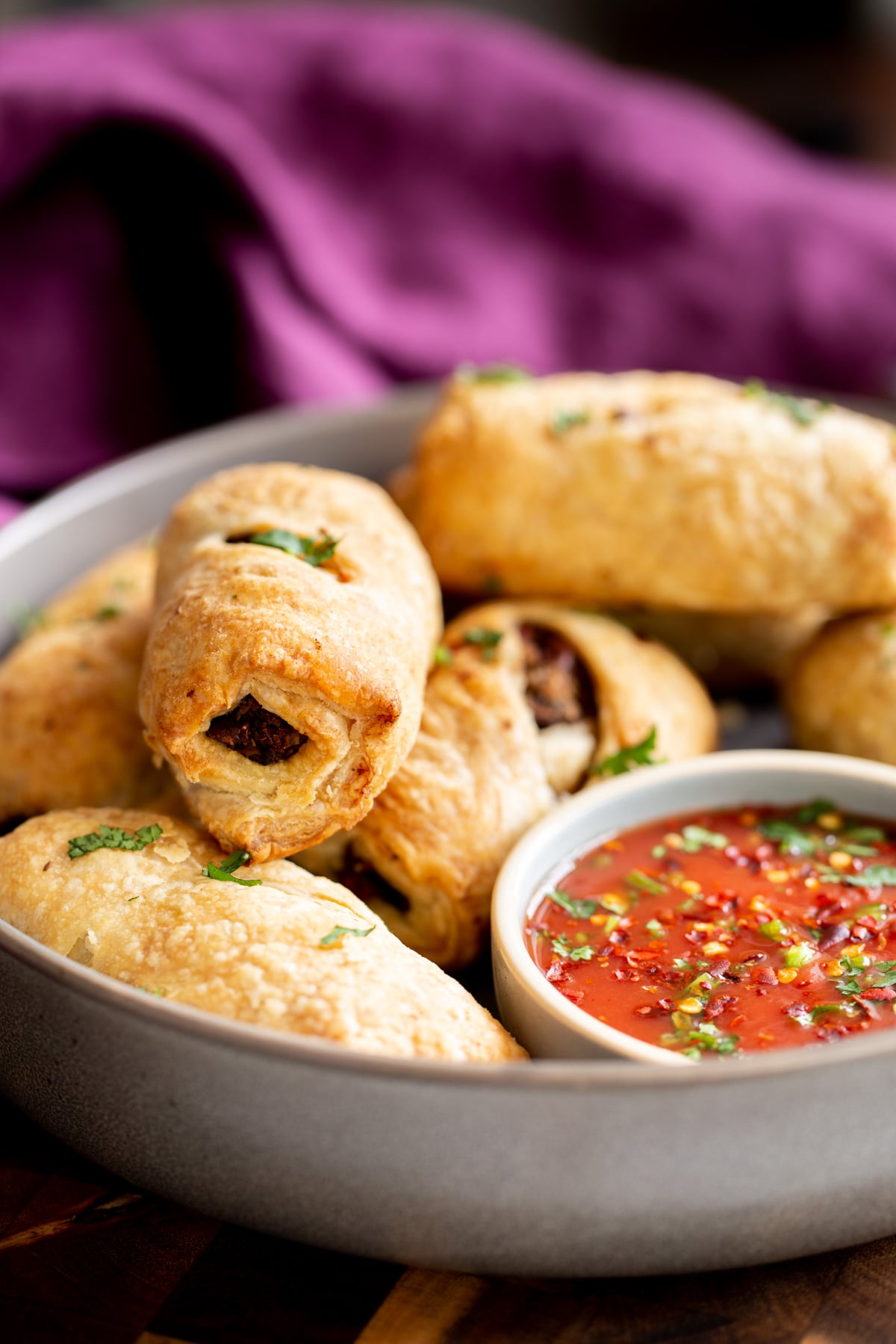 vegan sausage rolls with vegan puff pastry next to a side dish with tomato sauce