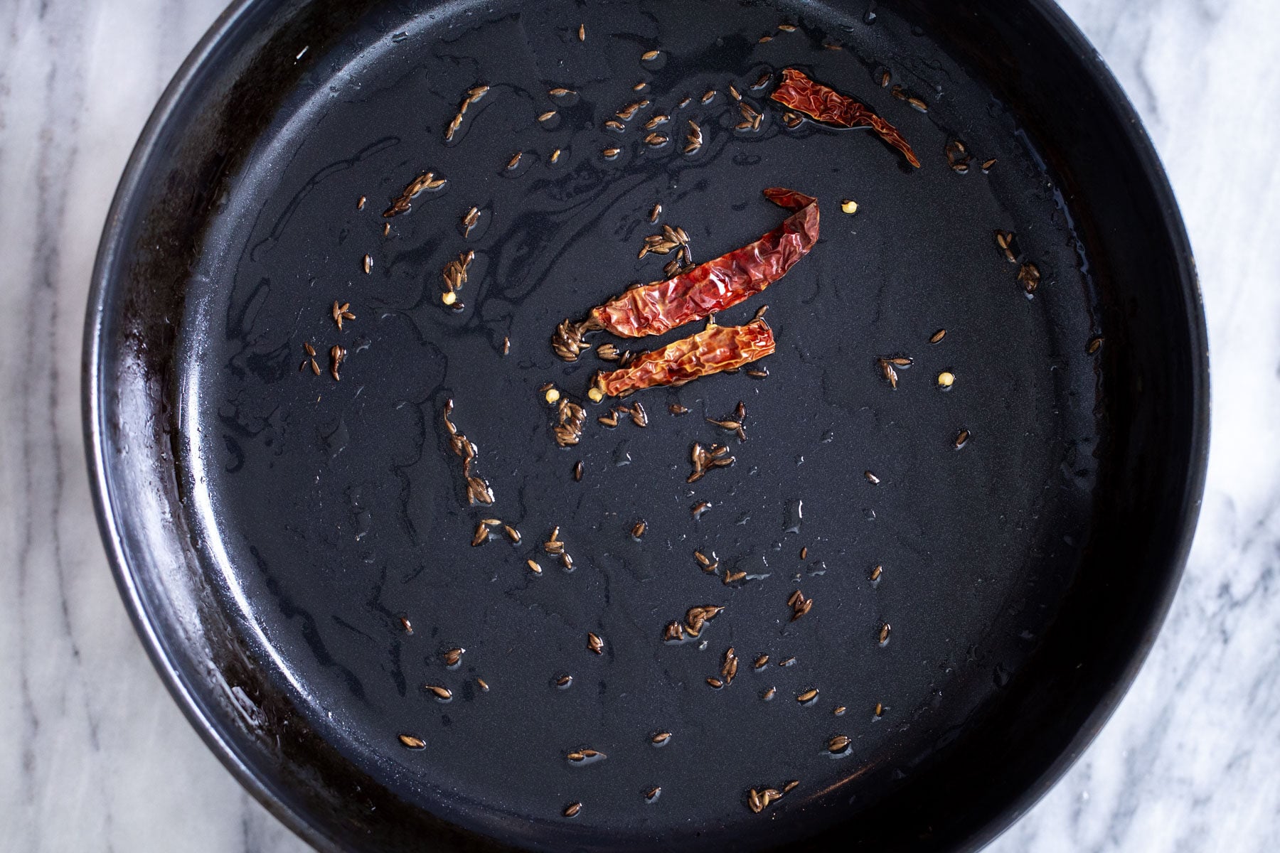 cumin seeds and chilies frying in oil to make curry