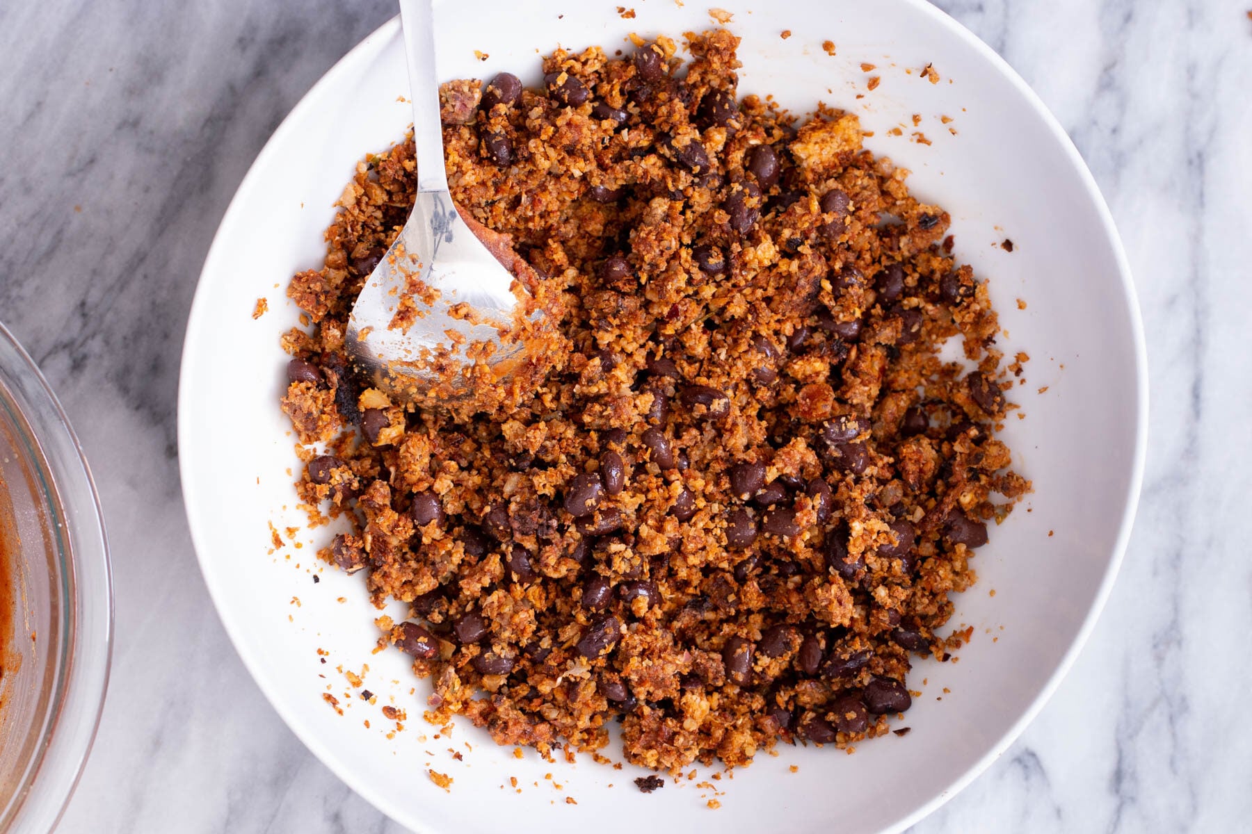 a small dish with cauliflower taco meat being mixed with kidney beans