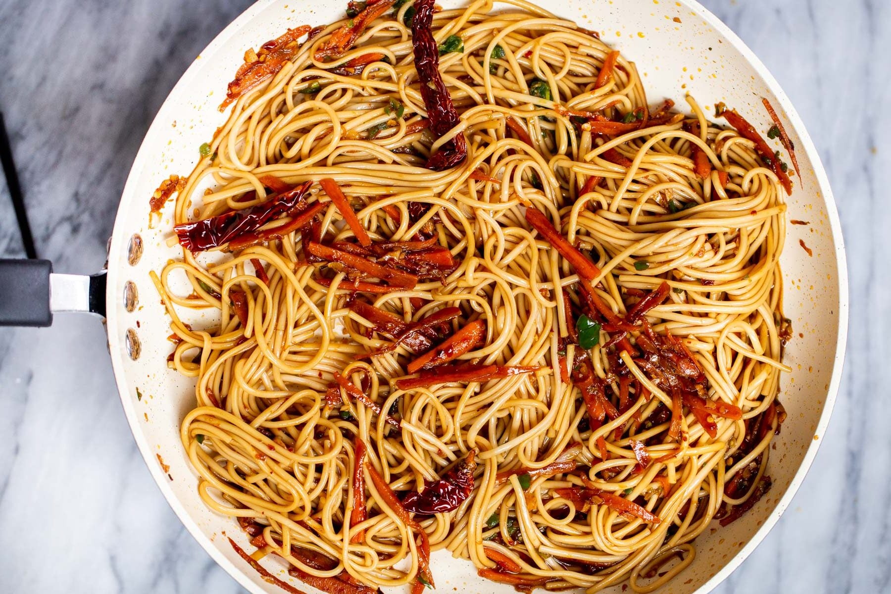 cooked lo mein noodles being tossed with sauce and sauteed veggies for making stir-fry