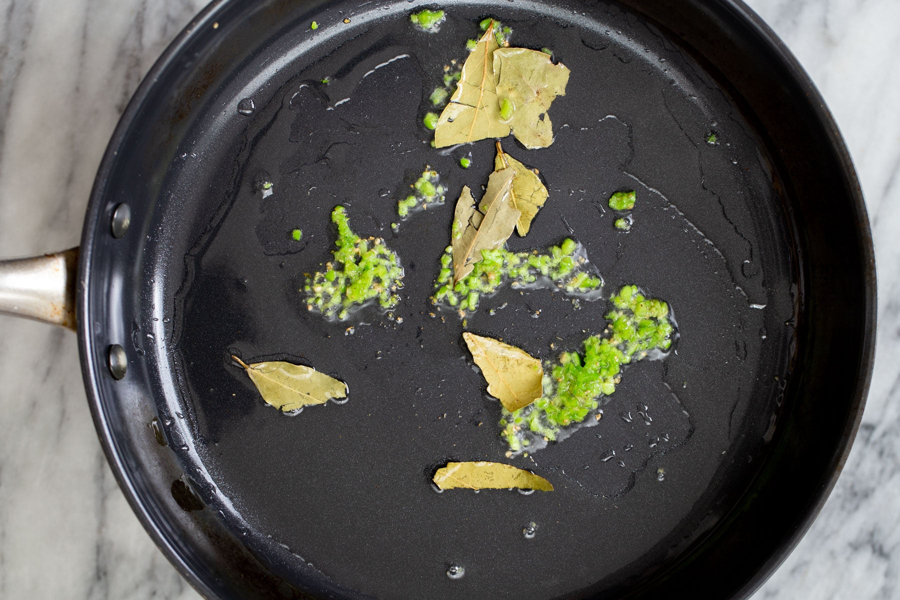 green chili and bay leaf in a sauteeing pan