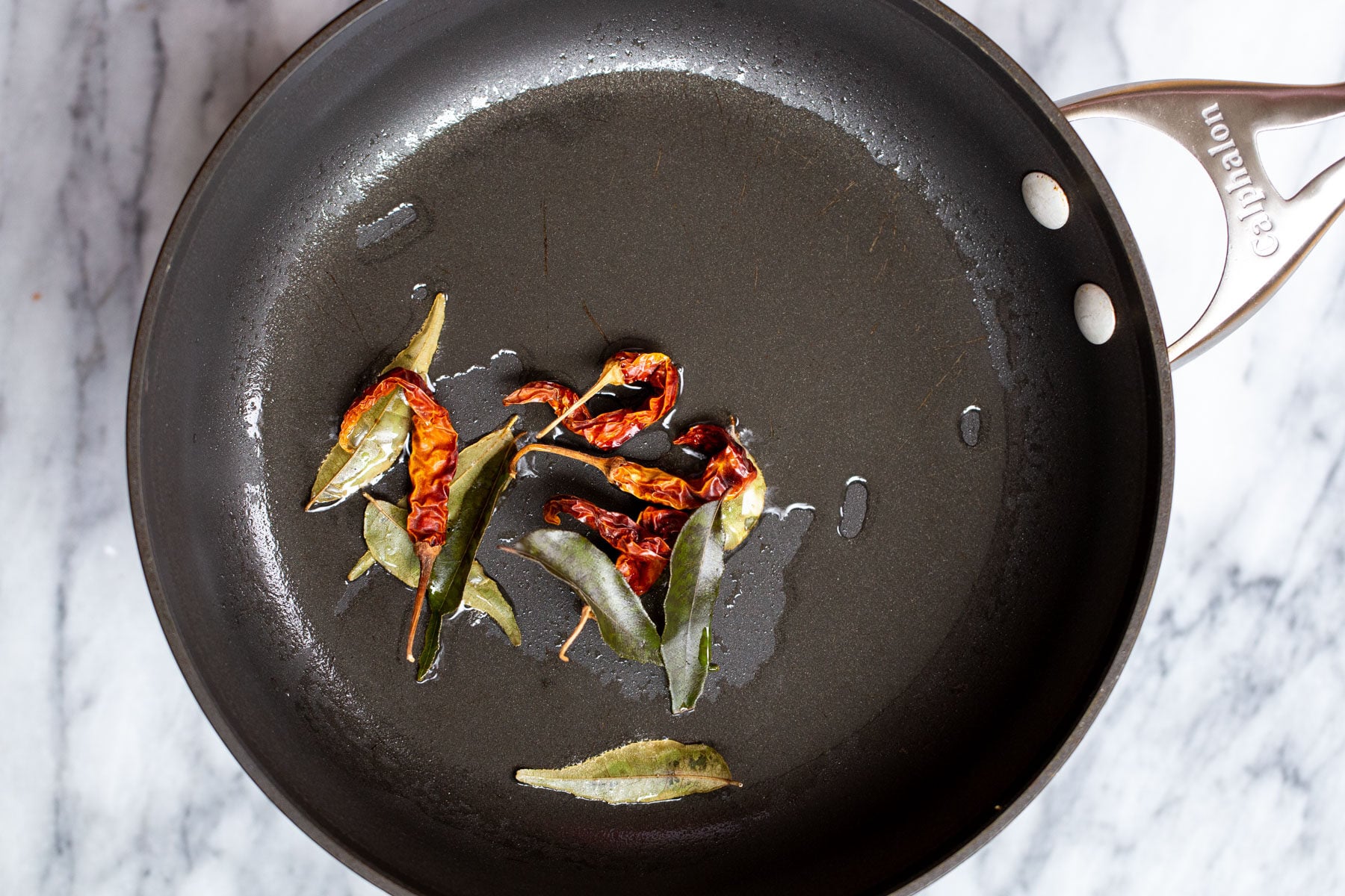 chilies and curry leaves in a black skillet
