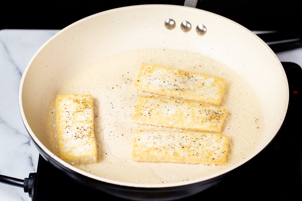 pan-fried sliced of tofu in a sauteeing pan 
