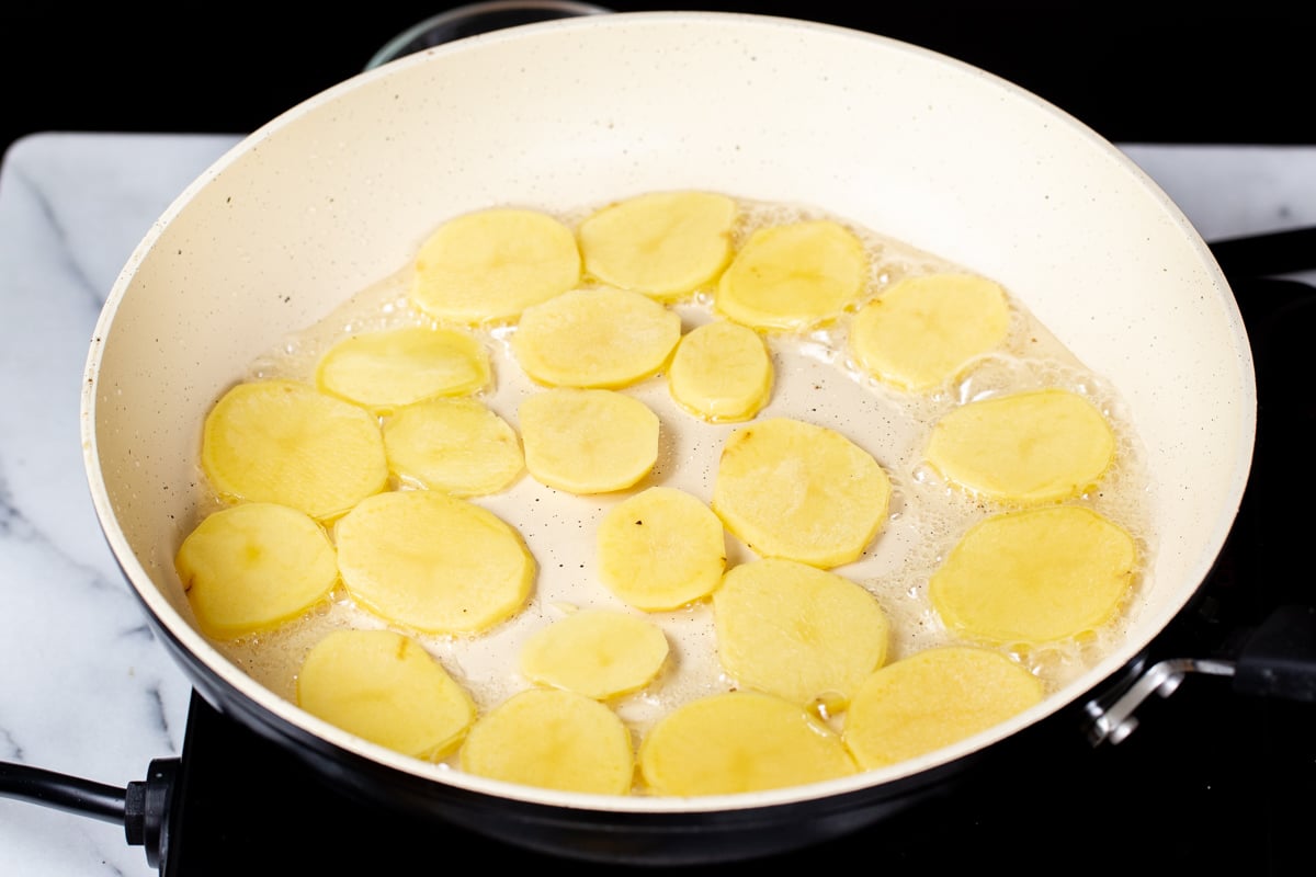 potato sliced being fried in pan 