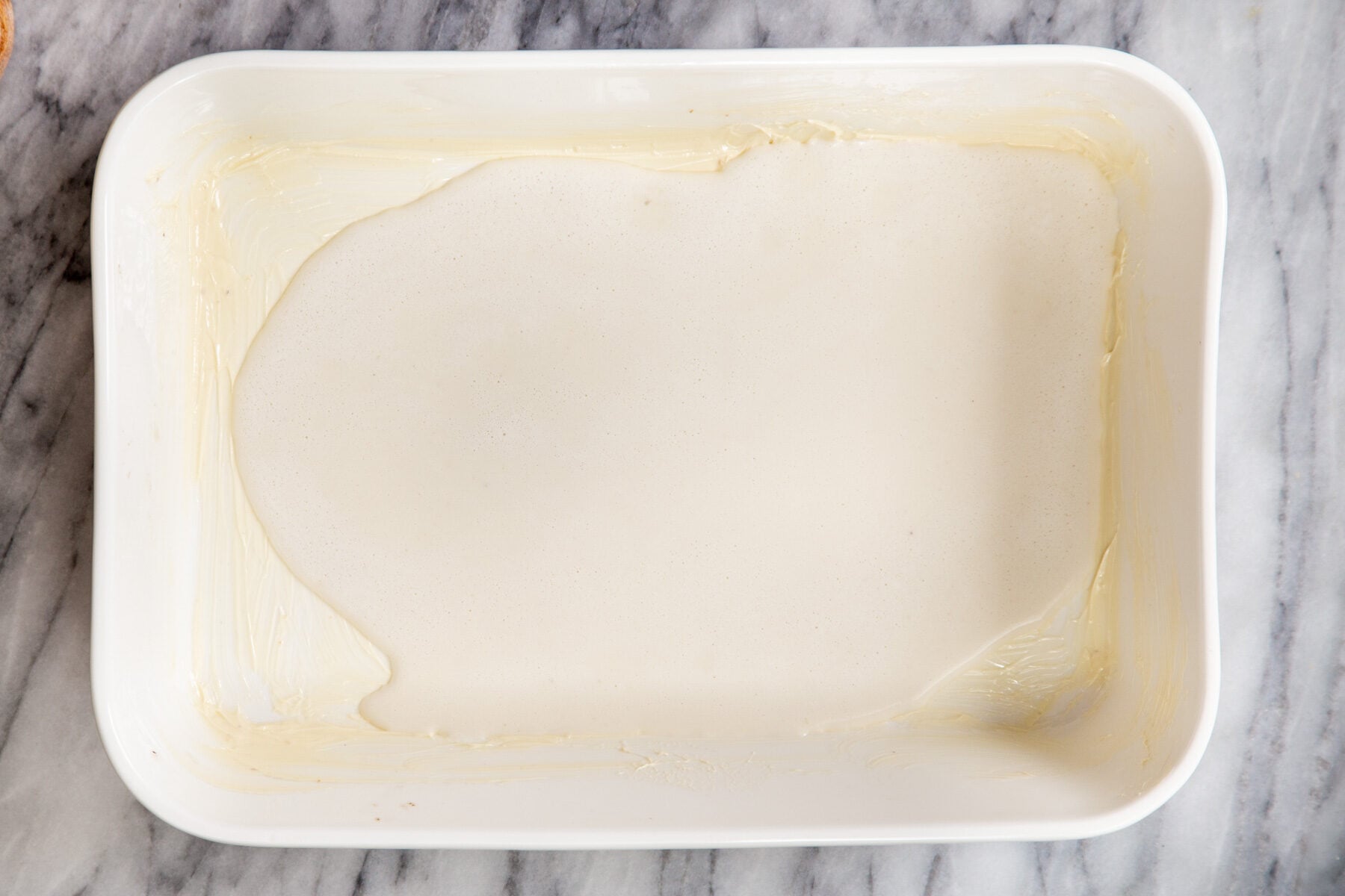 vegan cashew custard being poured into a casserole dish to make baked French toast