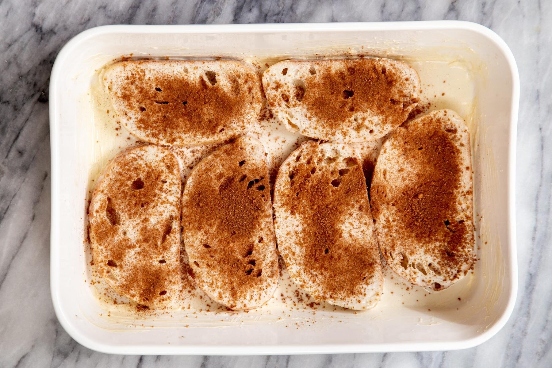 cinnamon and sugar being sprinkled over vegan french toast casserole