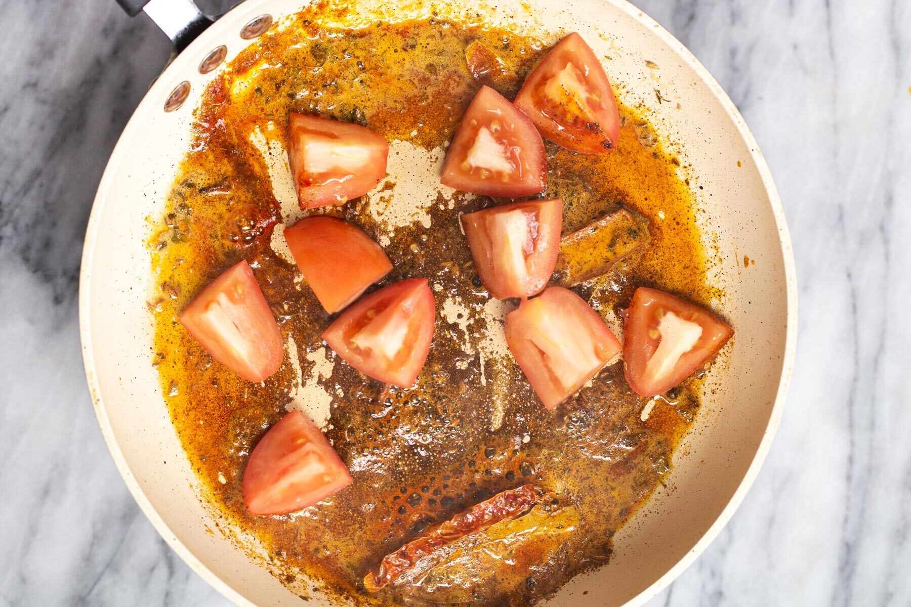 tomatoes being added to a pan with tempering