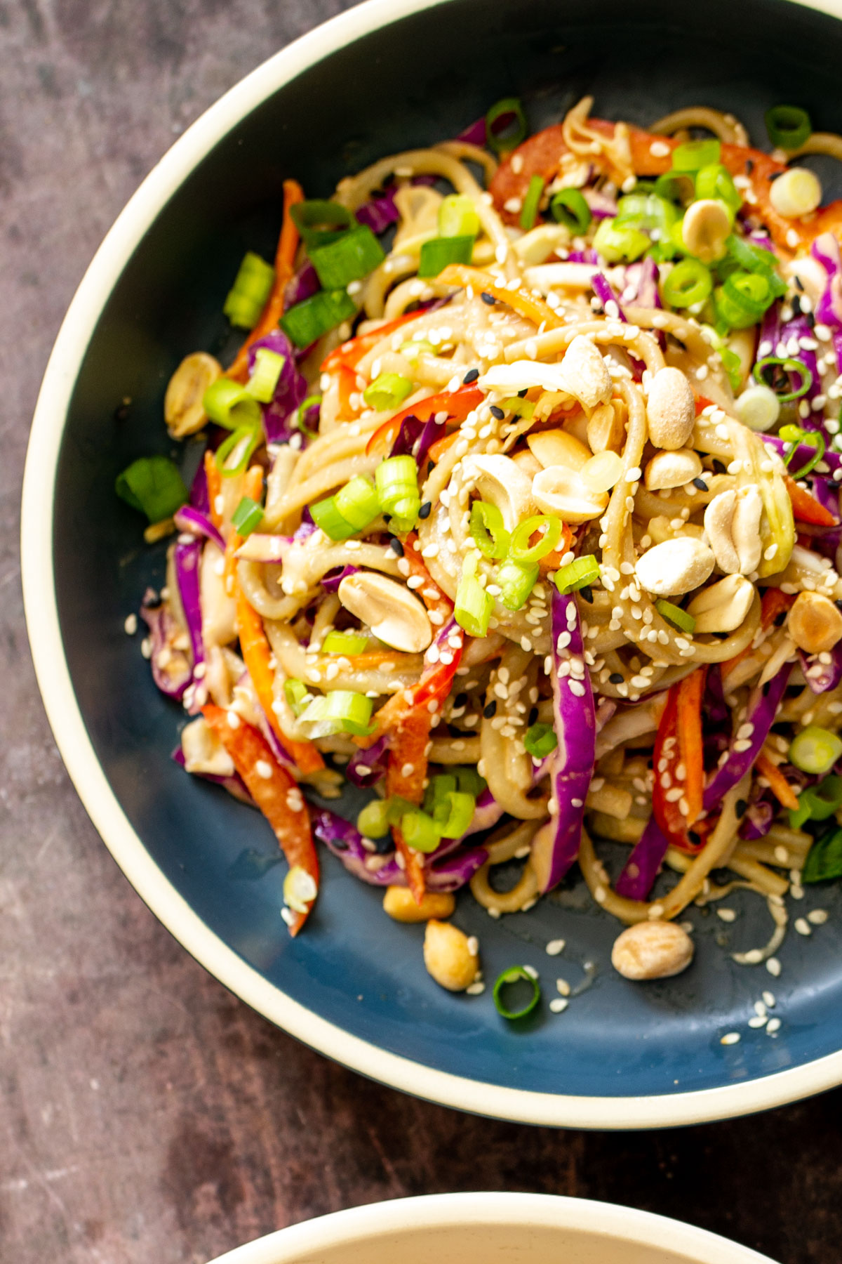 peanut sesame noodle salad with vegetables sprinkled with sesame seeds and peanuts