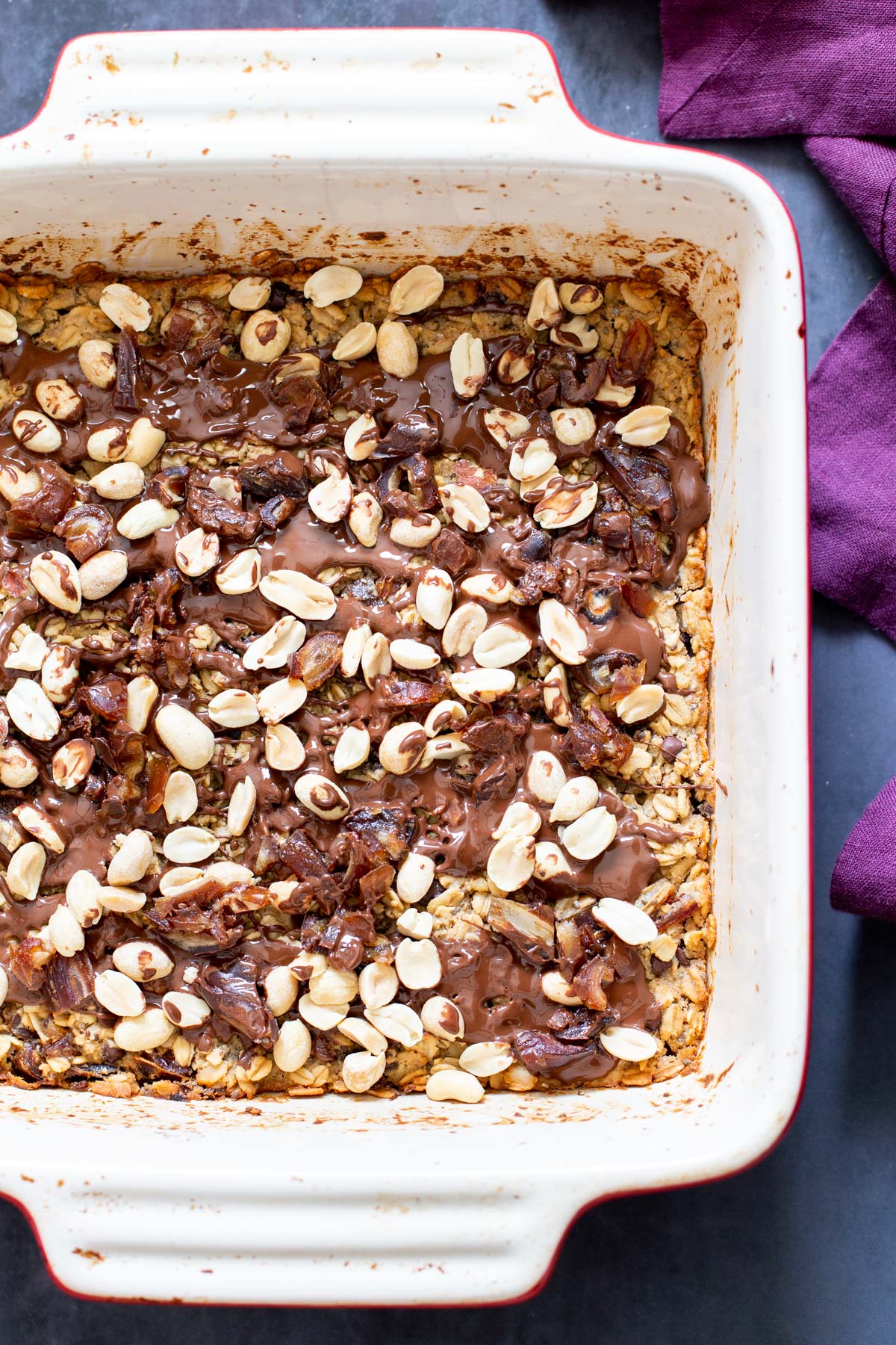 snickers baked oatmeal snickers baked oatmeal topped with peanuts and chocolate in a casserole dish