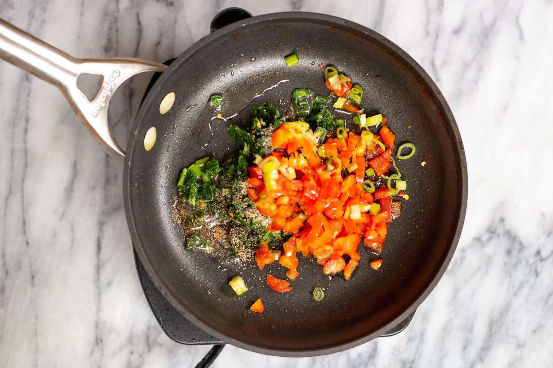 spinach and tomatoes in a black sauteeing pan
