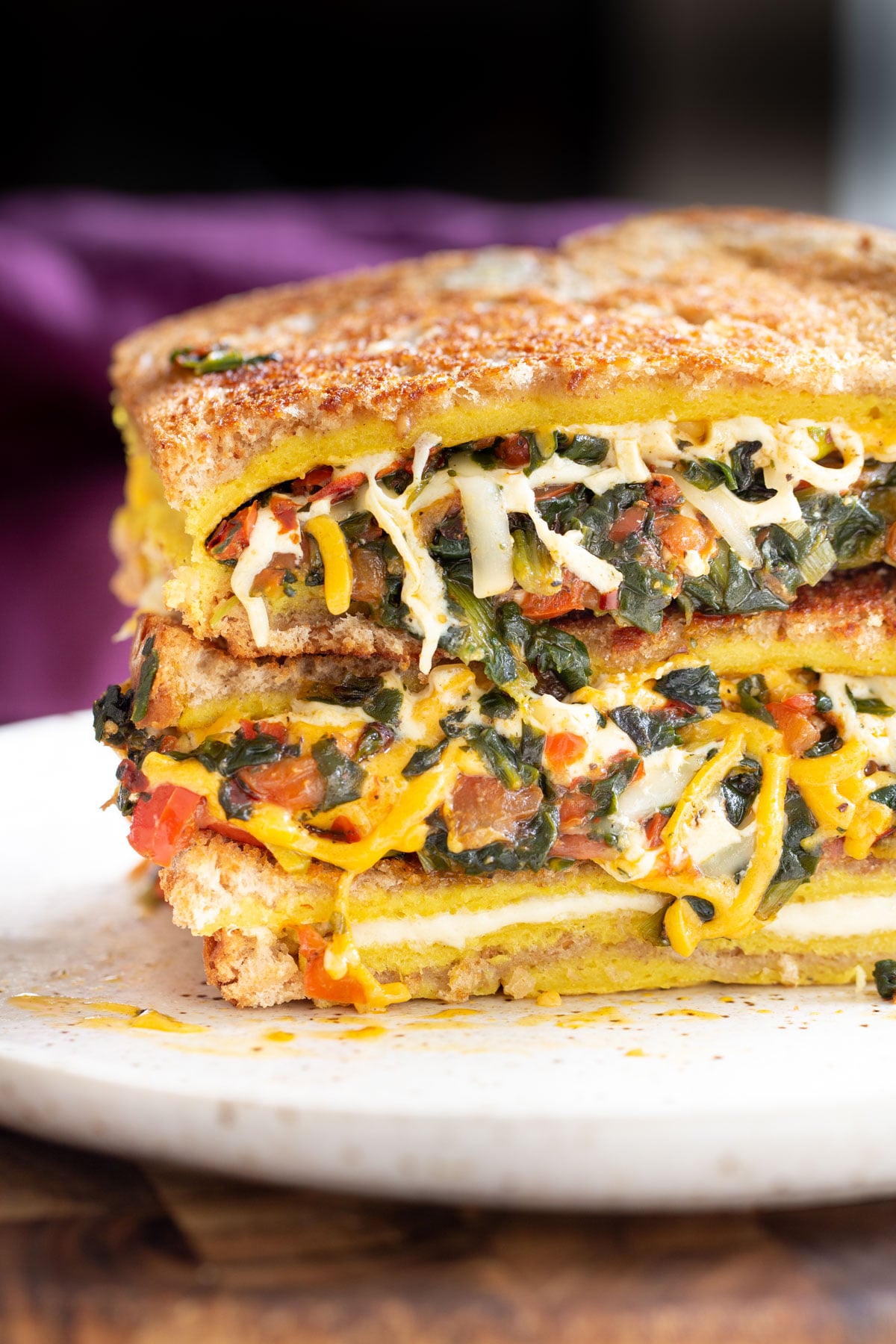 filled spinach and cheese vegan egg sandwiches stacked on a plate