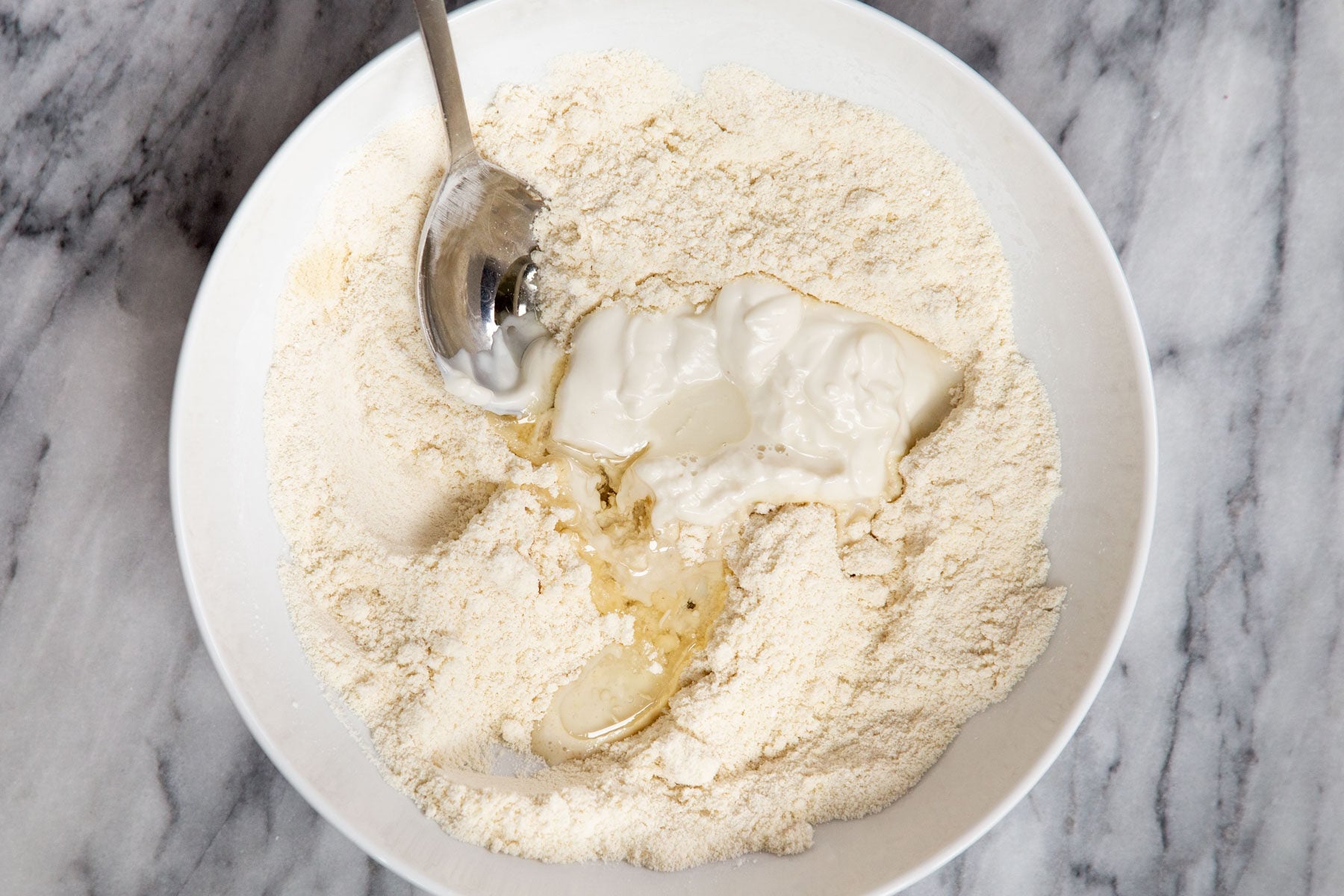 wet and dry ingredients being combined in a bowl for making glutenfree pizza dough