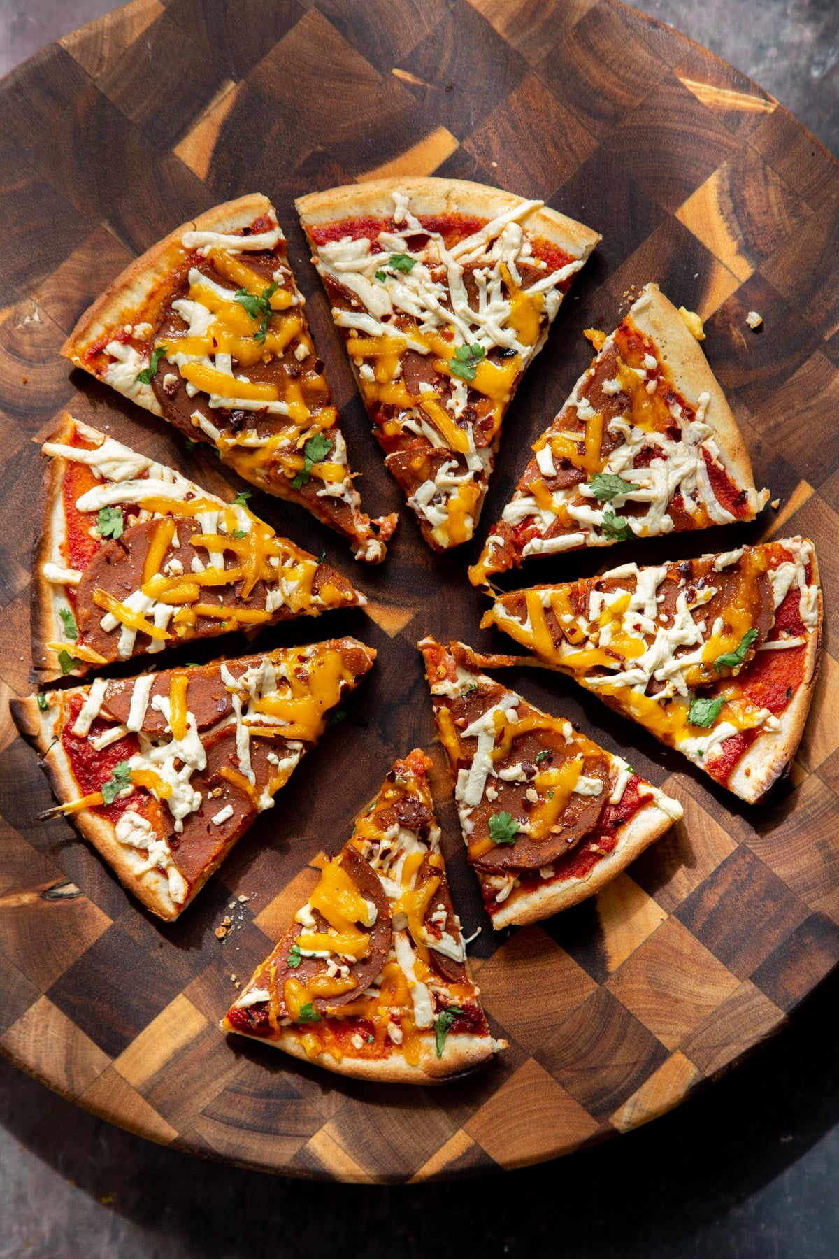 vegan pepperoni pizza on a wooden board, sliced.