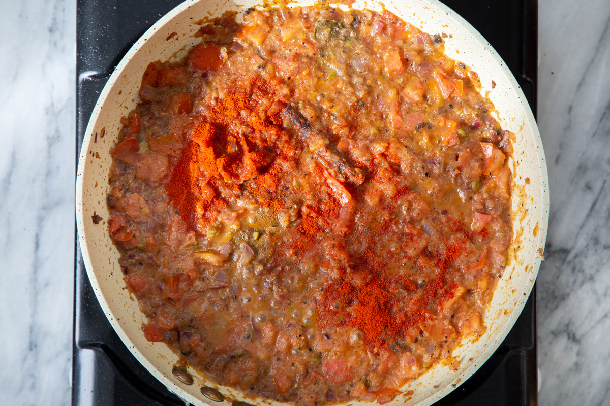 chili powder and paprika being added to frying pan