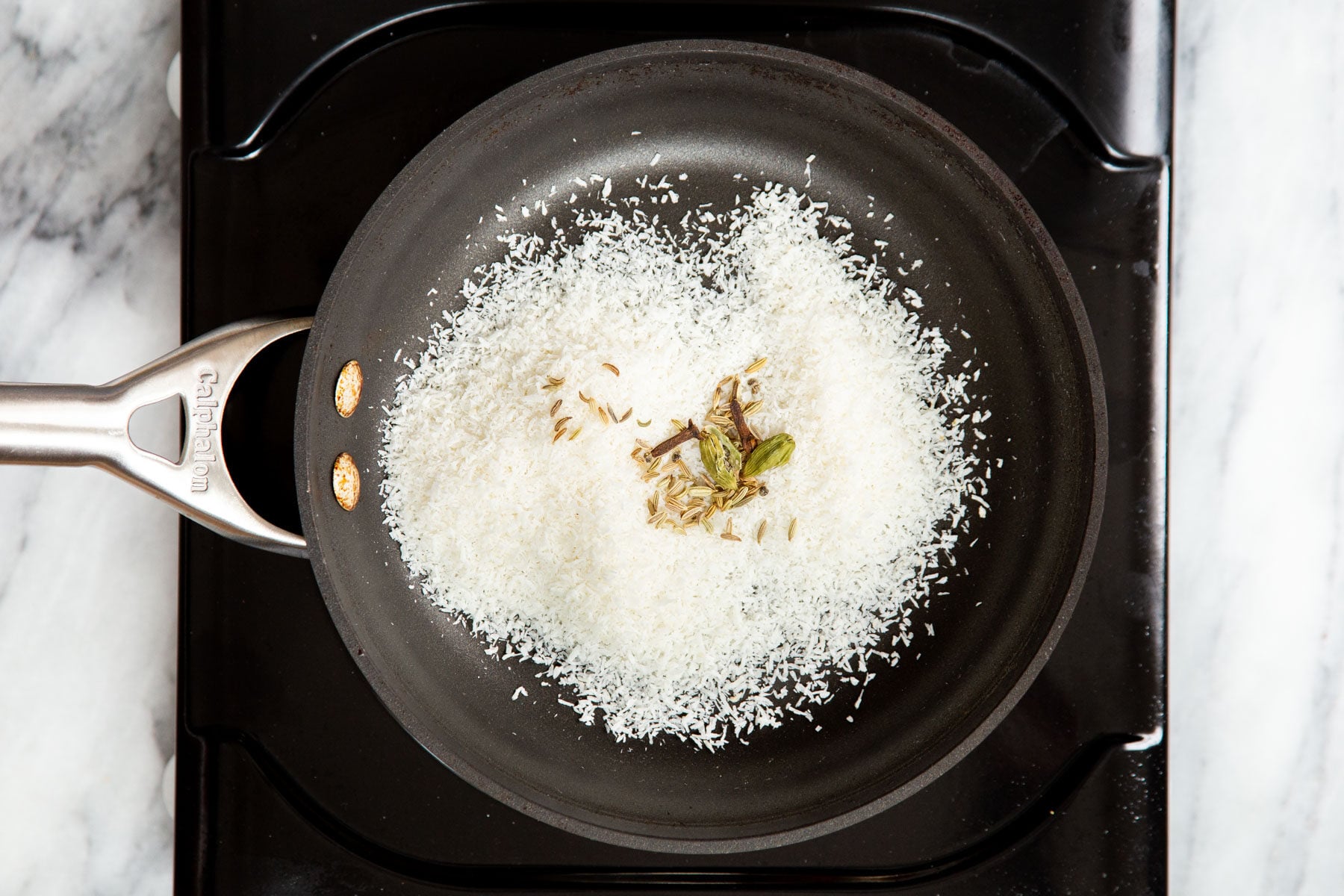 coconut being toasted in a black sauteeing pan