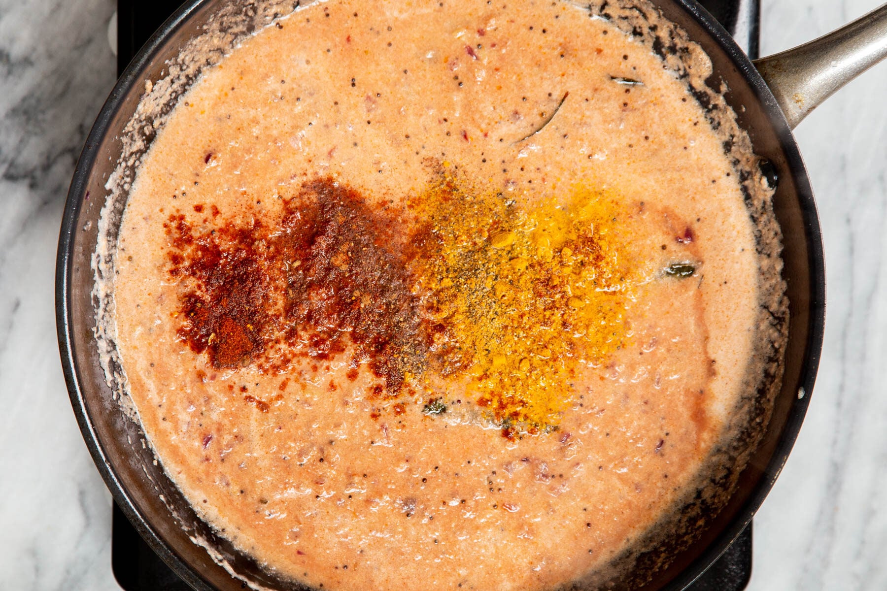 ground spices being added to malabar curry gravy