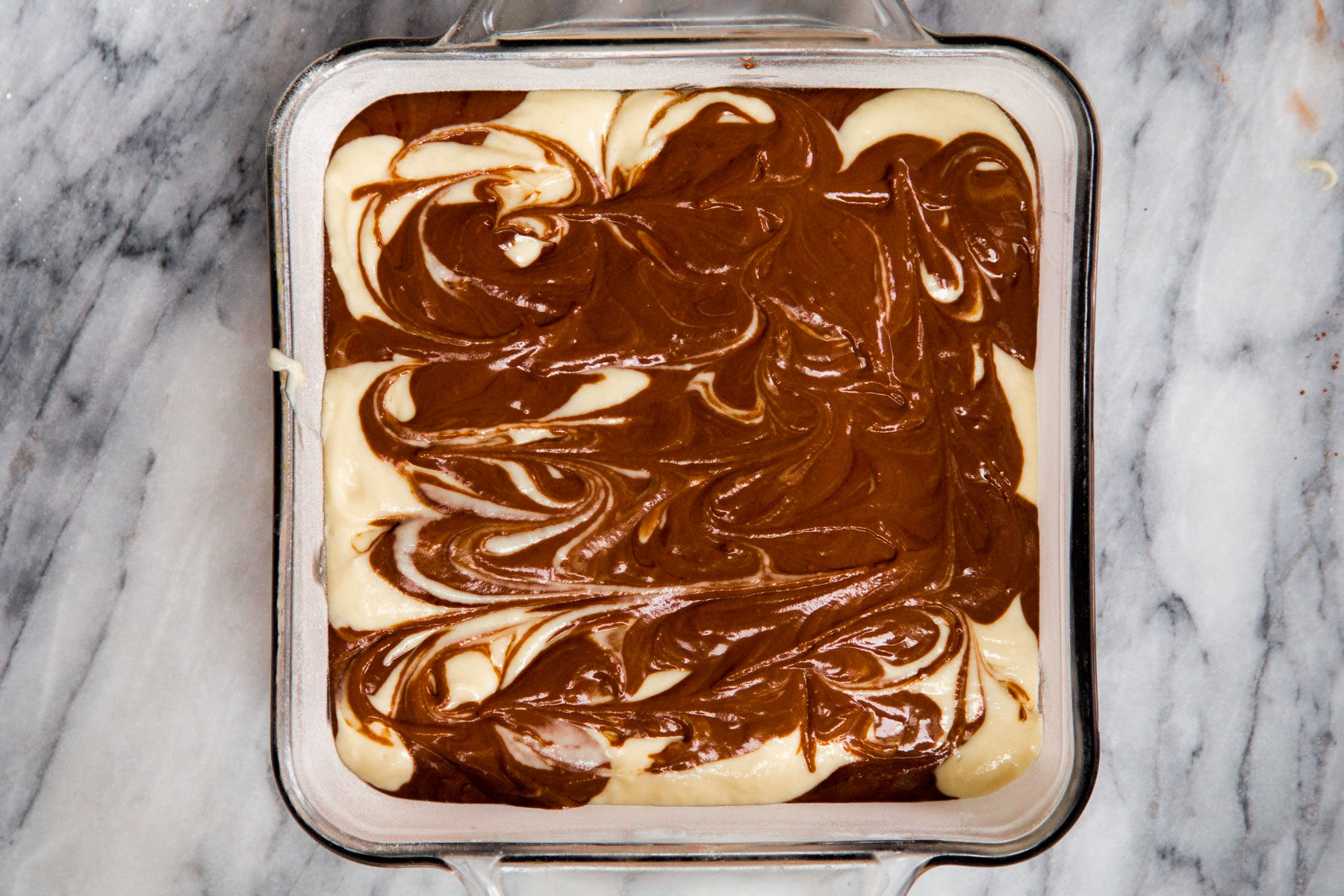 swirled vegan marble cake batter in a square cake pan