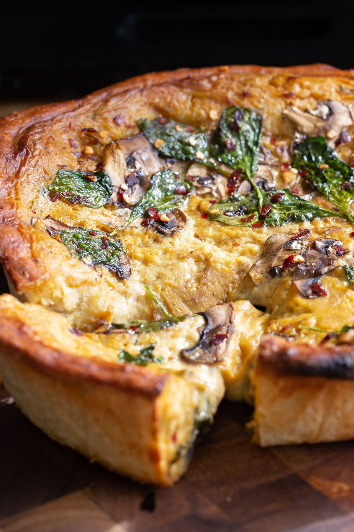 vegan deep dish pretzel crust pizza filled with cheese sauce, mushrooms and spinach