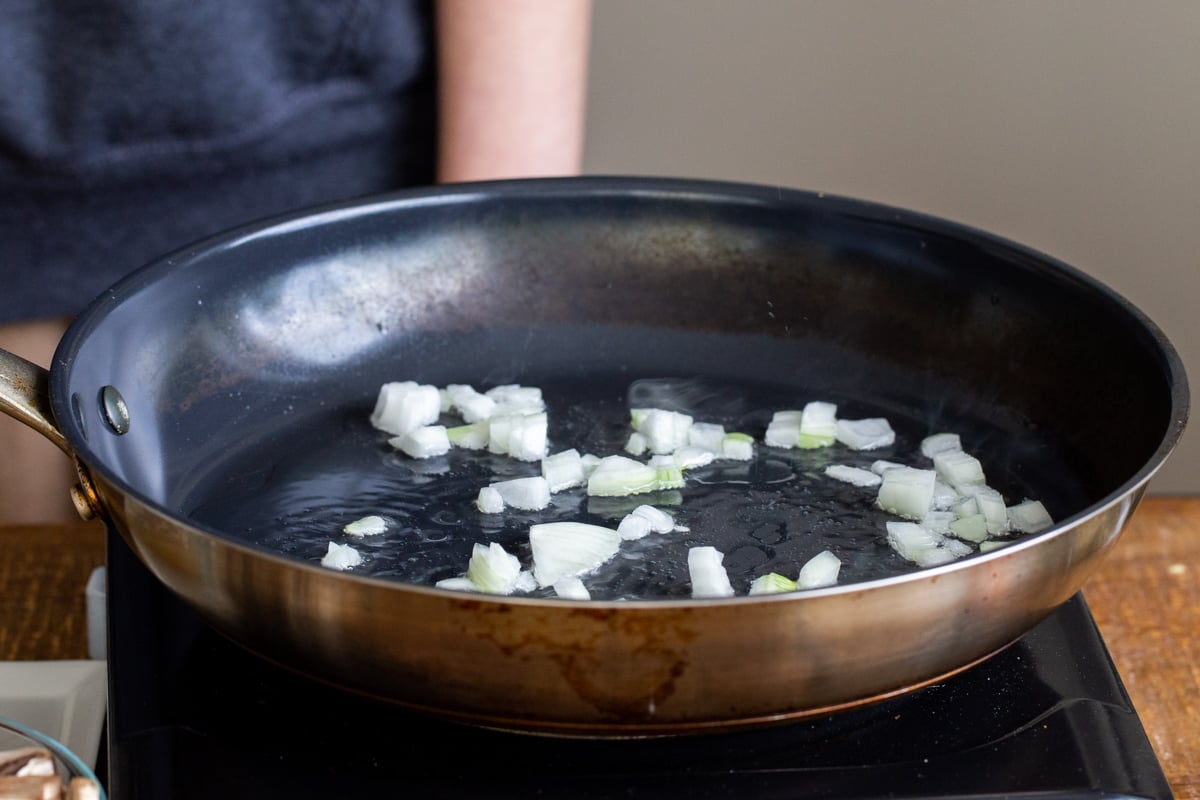 minced onions being sauteed in a black skillet