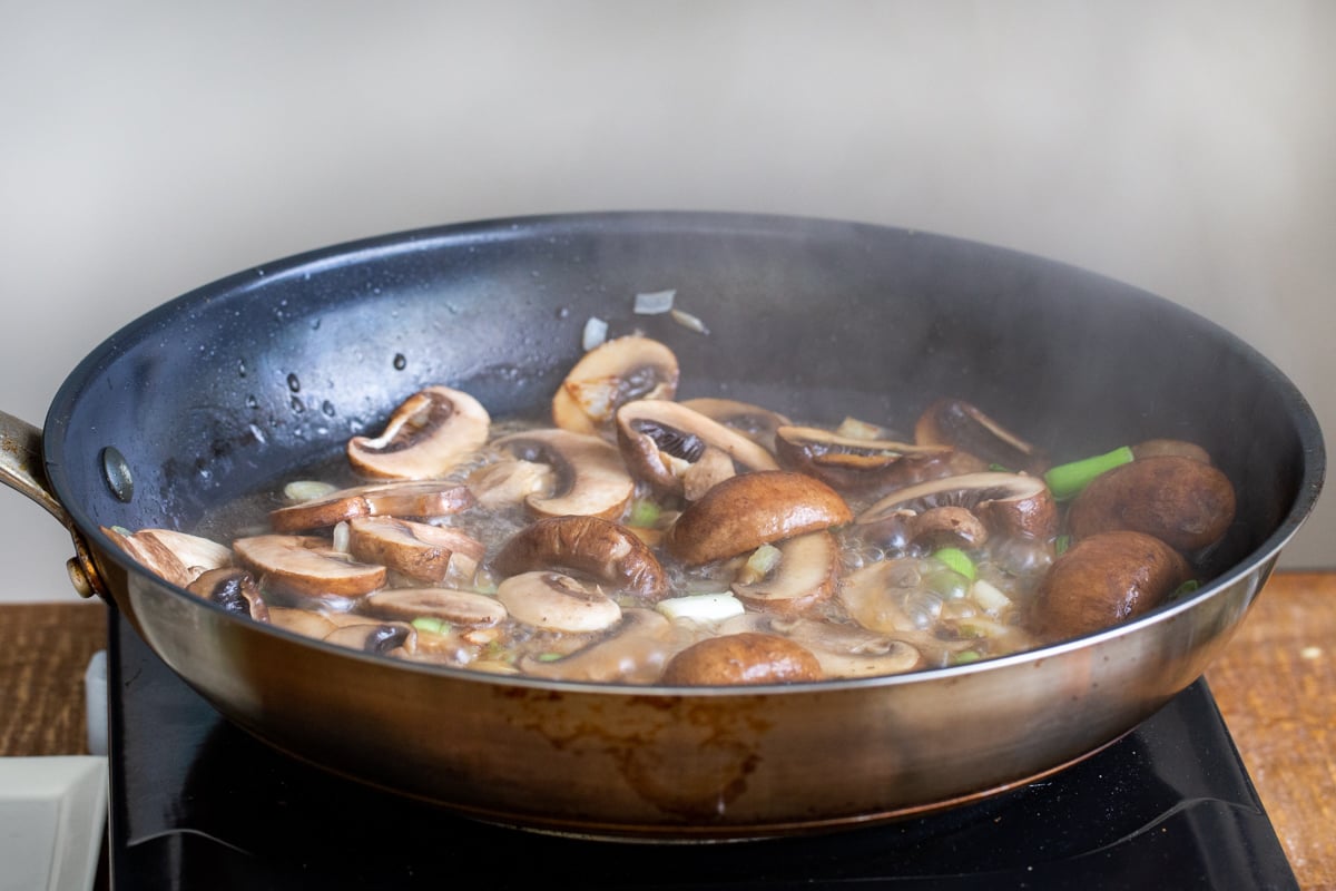 mushrooms sauteeing in a black pan
