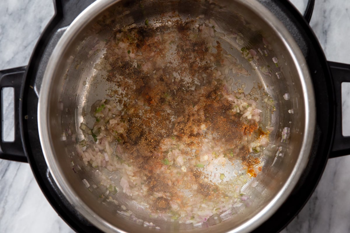 Indian spices being added to sauteed onions and garlic 