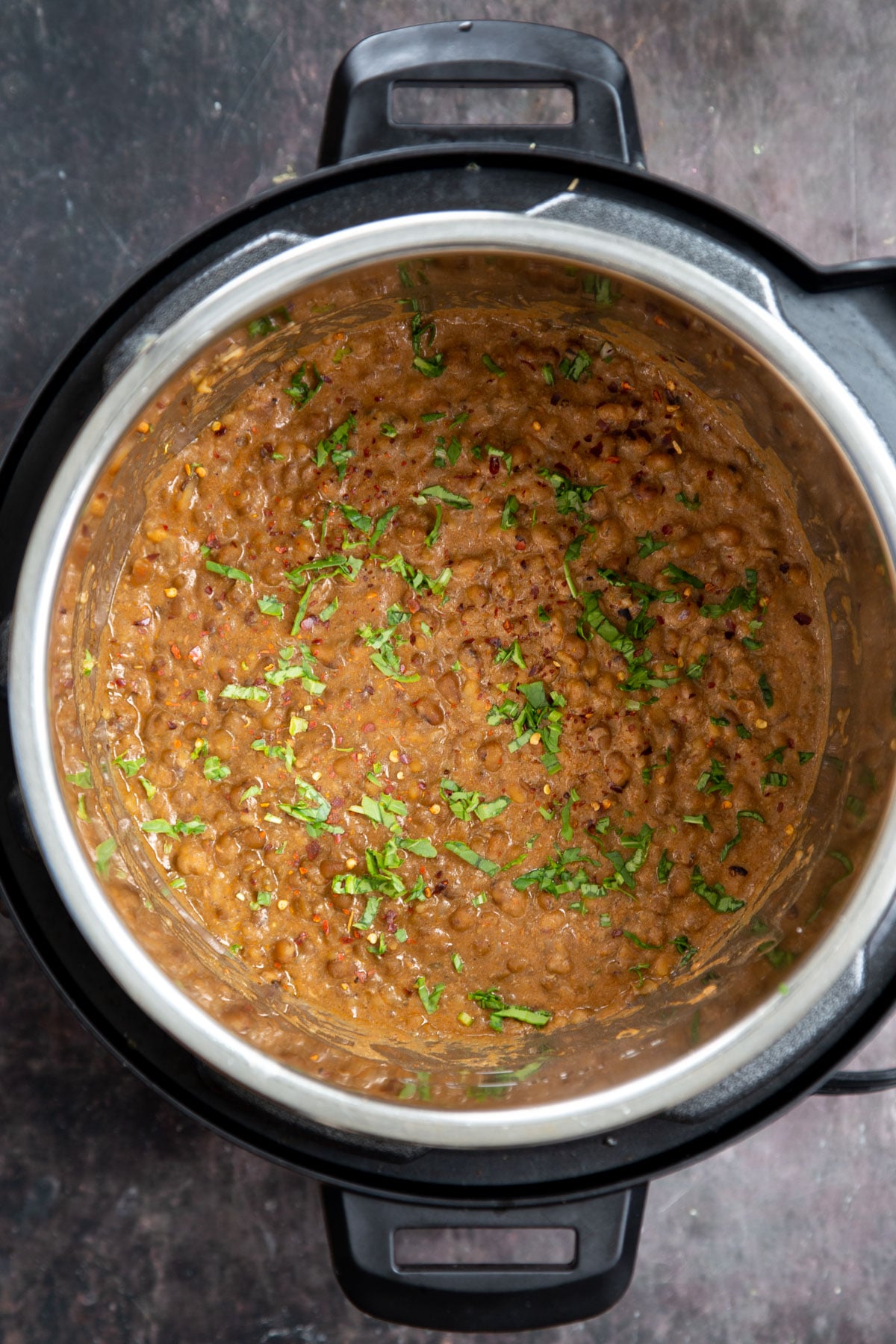 freshly chopped herbs being sprinkled into an Instant pot with creamy mung bean stew 