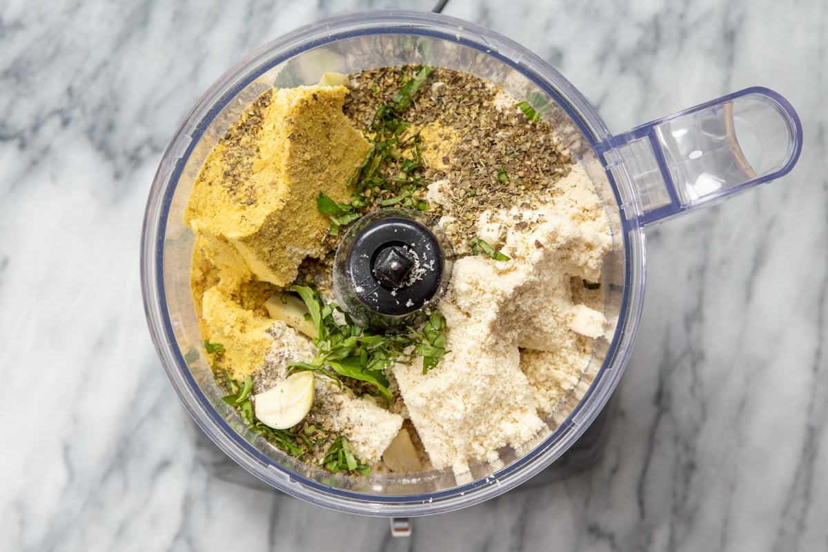 tofu, nutritional yeast, spinach and vegan parmesan cheese in the bowl of a food processor 
