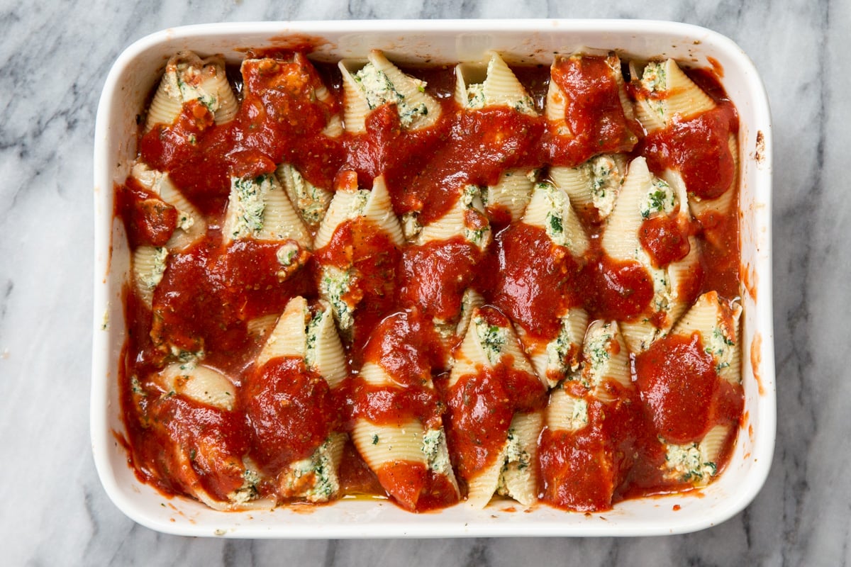 stuffed shells placed in a casserole dish with marinara sauce 
