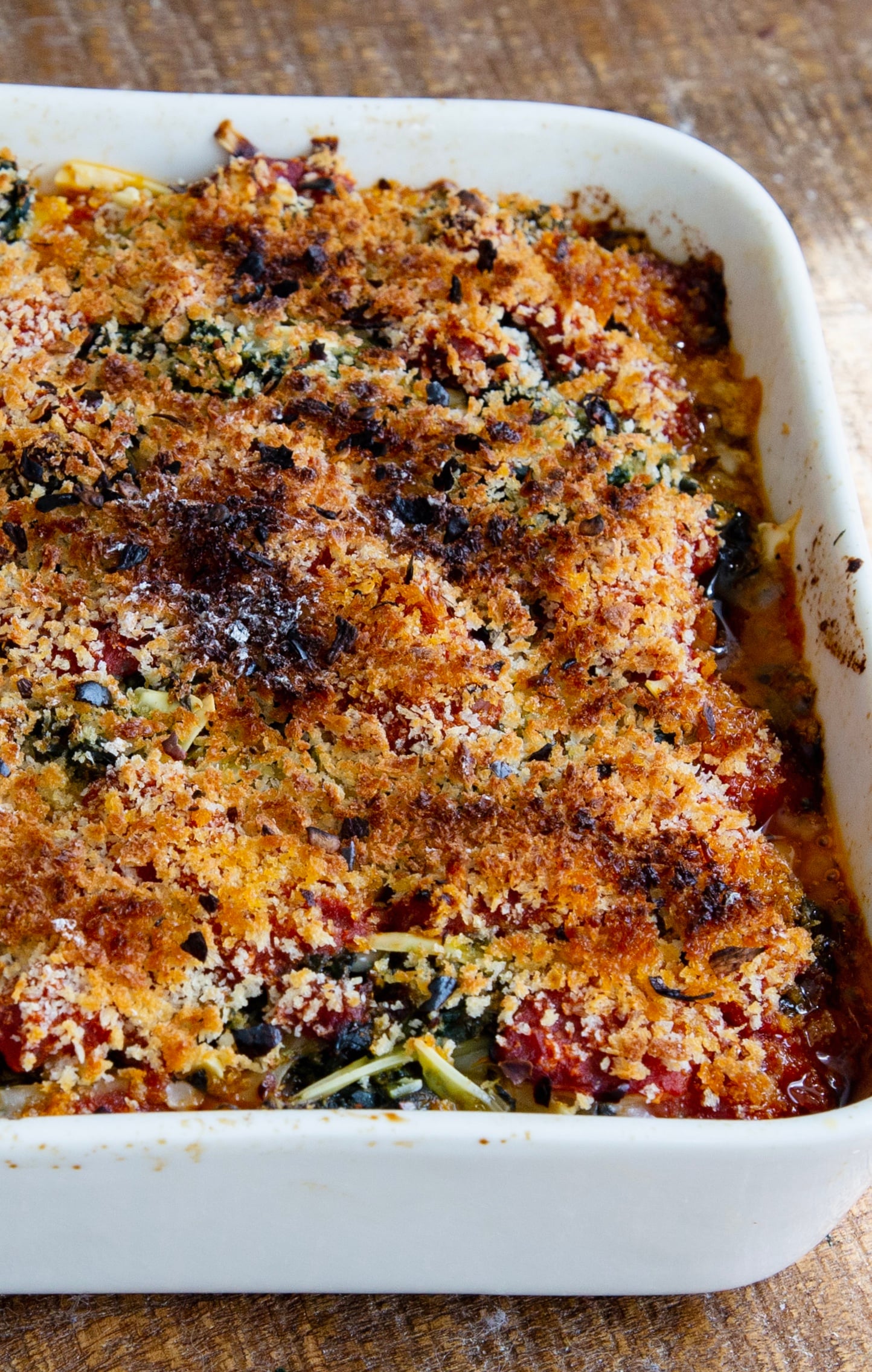 a baking dish with tofu parmigiana bake with spinach, cheese and marinara sauce