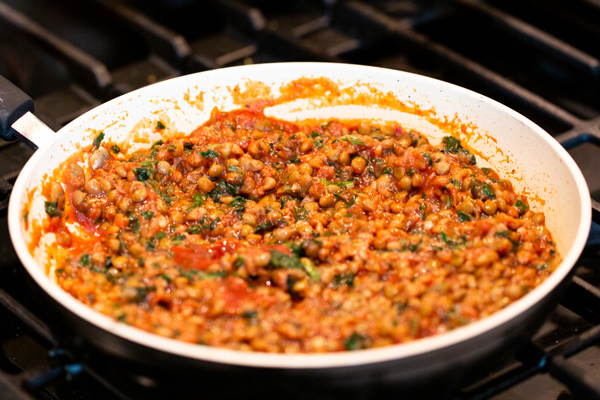 lentils and spinach cooking in tomato sauce in a pan