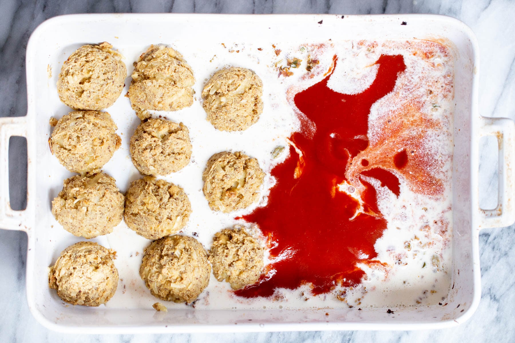 baked vegan tofu koftas in casserole dish with cashew cream and tomato sauce
