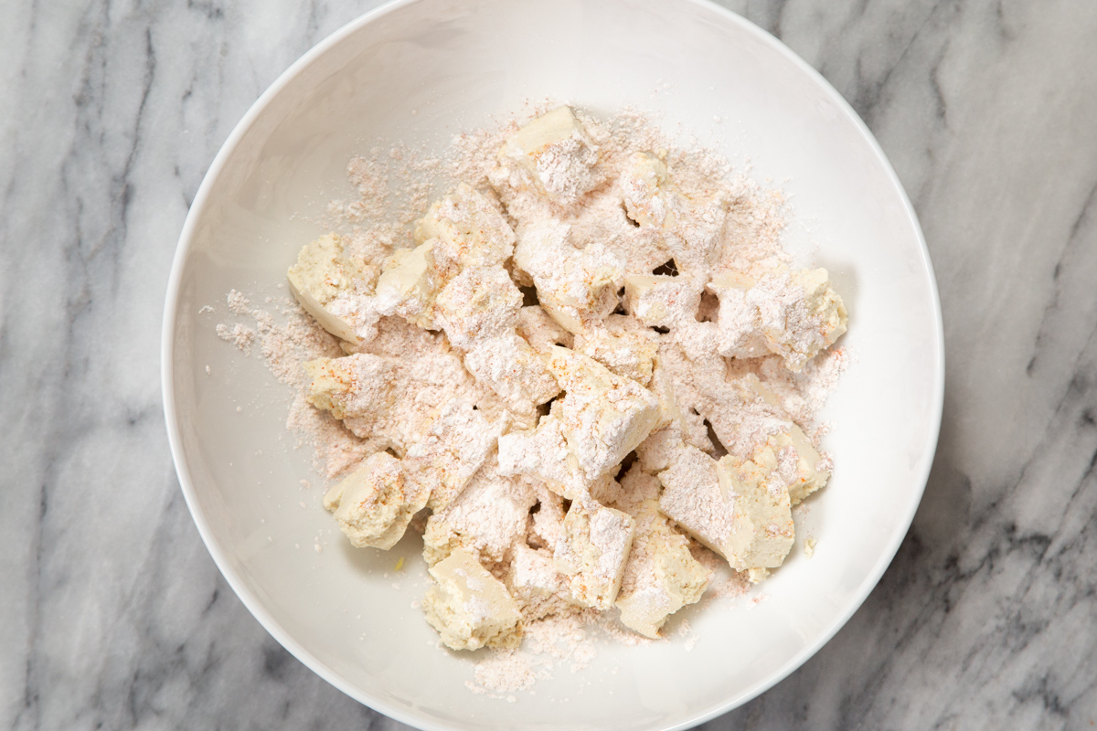 torn up tofu in a white bowl coated with spiced cornstarch