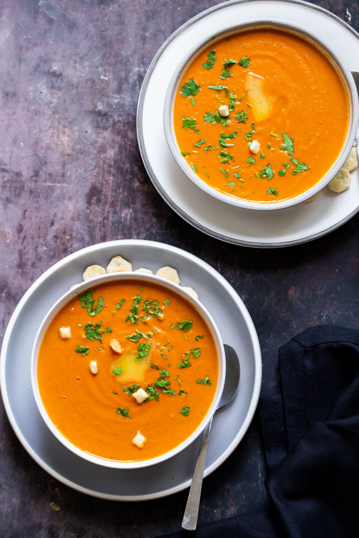 two bowls of vegan roasted tomato soup sprinkled with fresh herbs