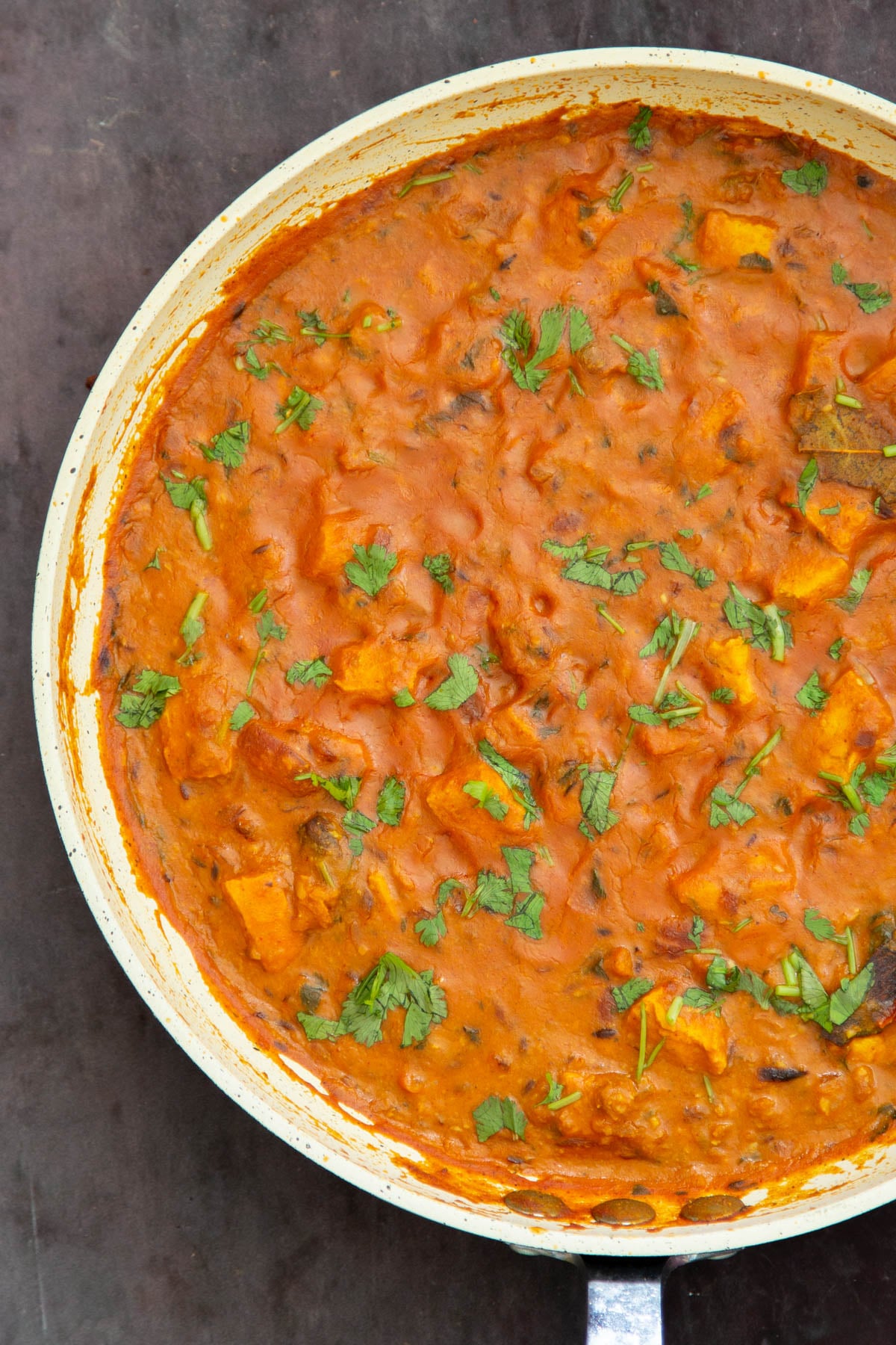 a pan with vegan balti chicken sprinkled with cilantro