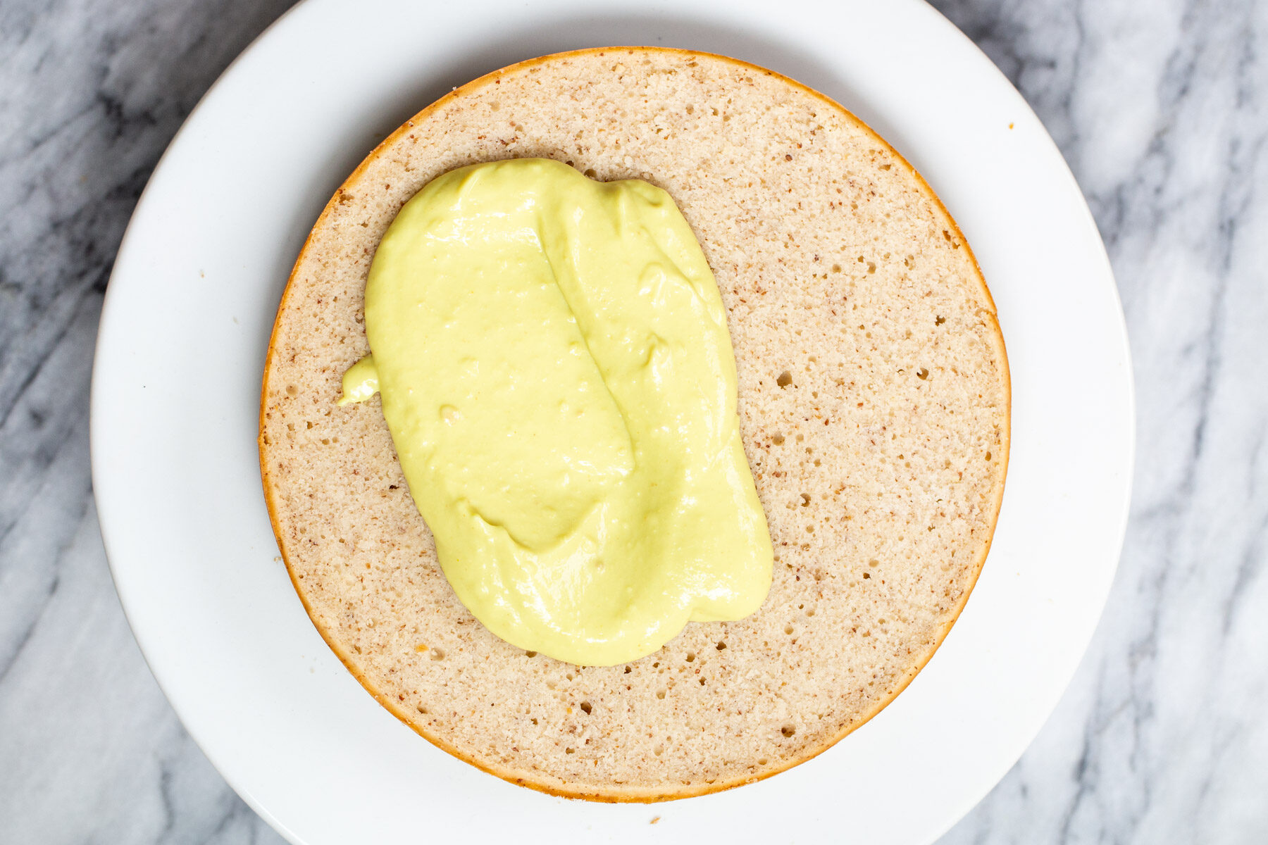 vegan custard being spread on a cake layer