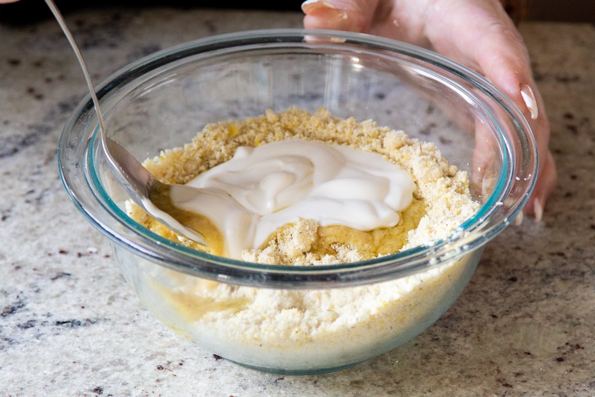 liquid ingredients being added to dry ingredients in a glass bowl