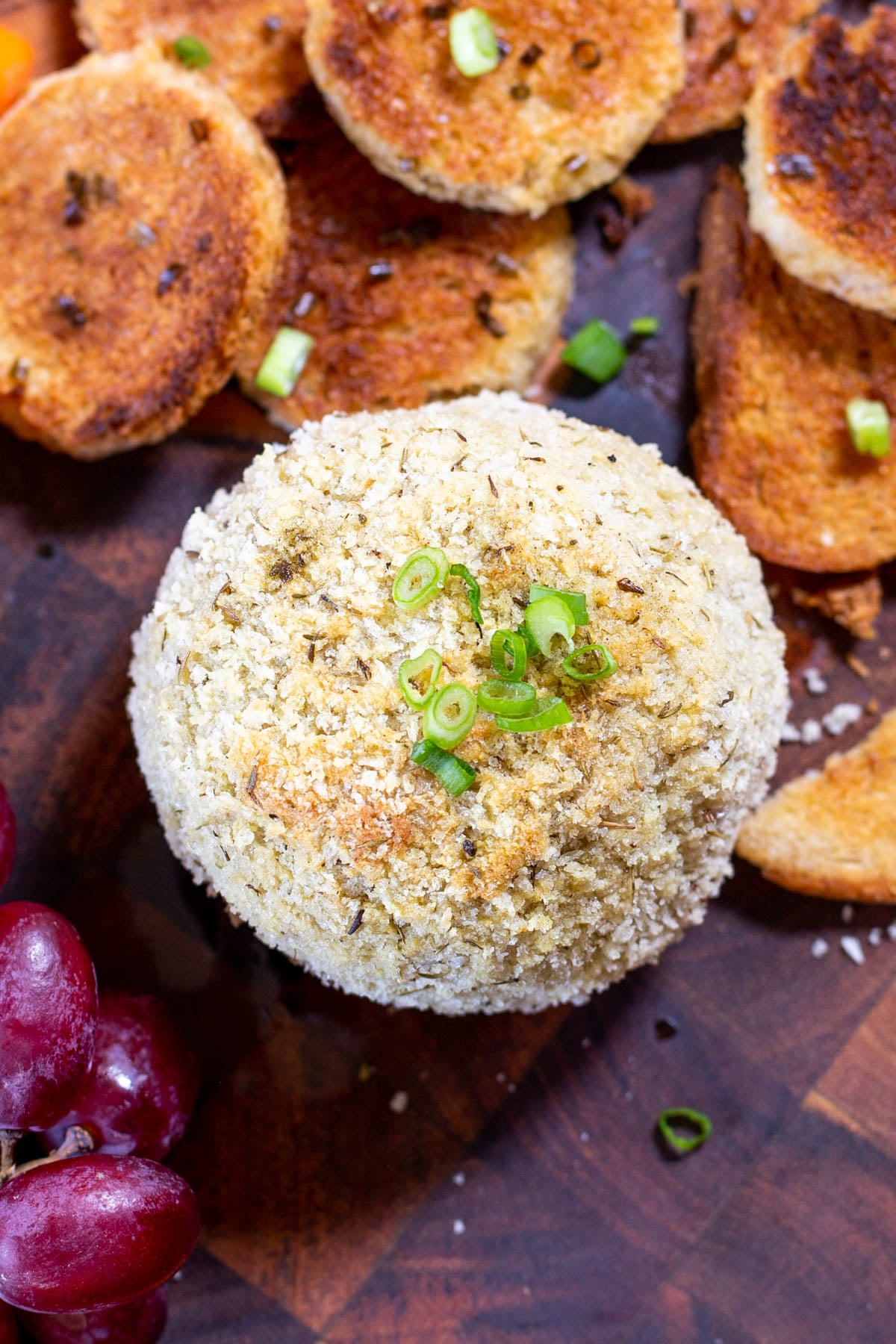 overhead shot of a vegan stuffing flavored cheeseball with crackers and grapes on the side