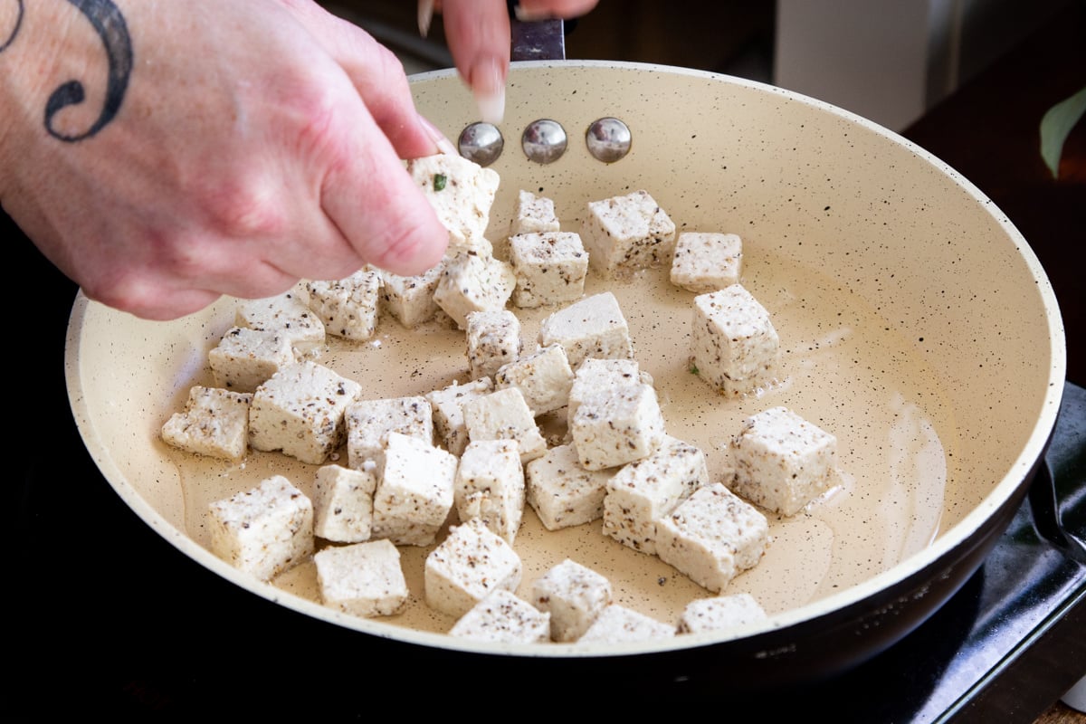 seasoned tofu cubes being fried in a pan