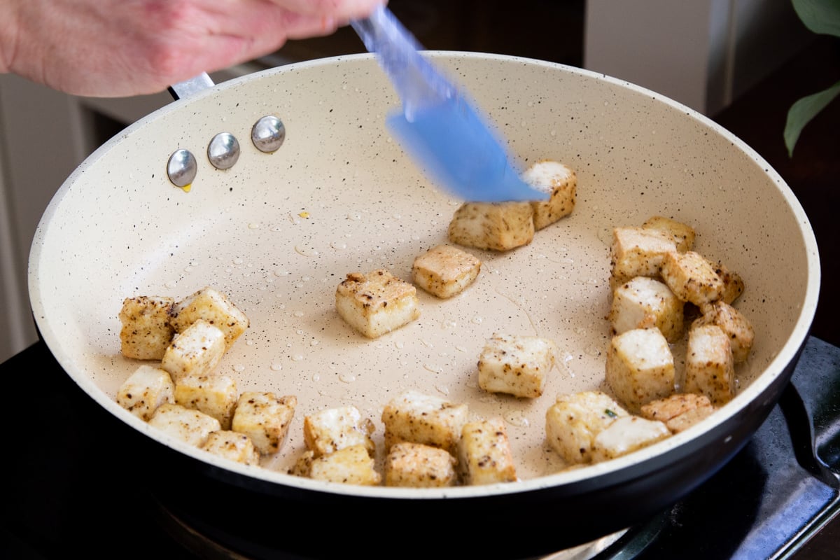 coated tofu being fried in a pan until crispy