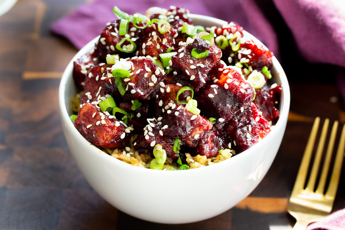 a small bowl of vegan blackberry gochujang tofu served over rice