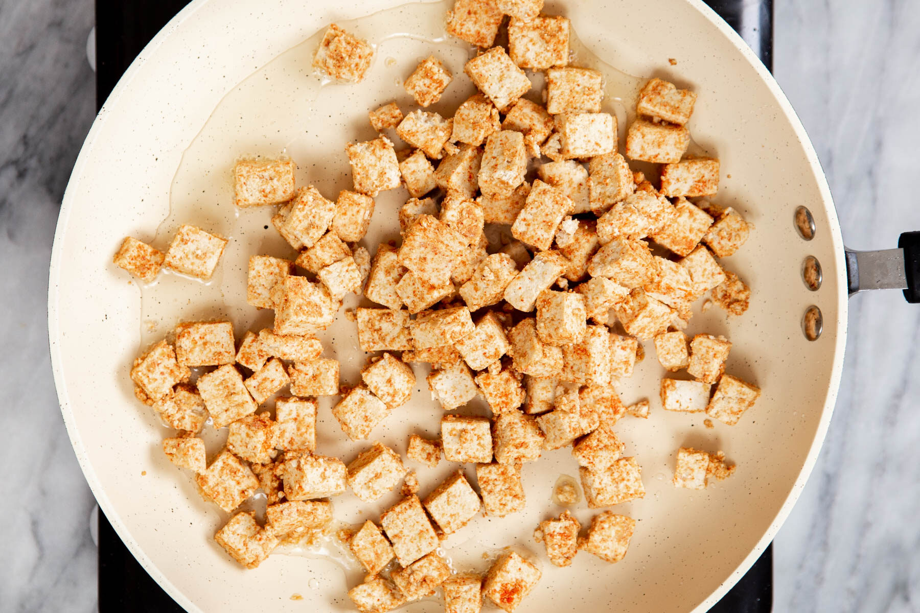 marinated cubes of tofu frying in a pan