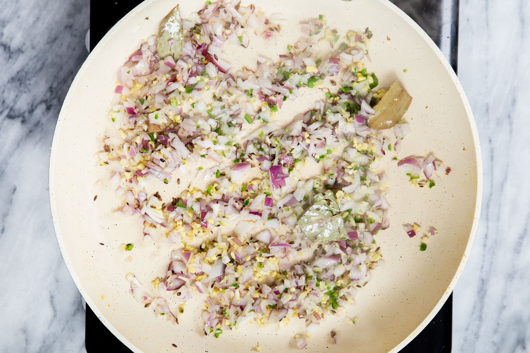 diced onions and ginger sauteeing in a pan with spices